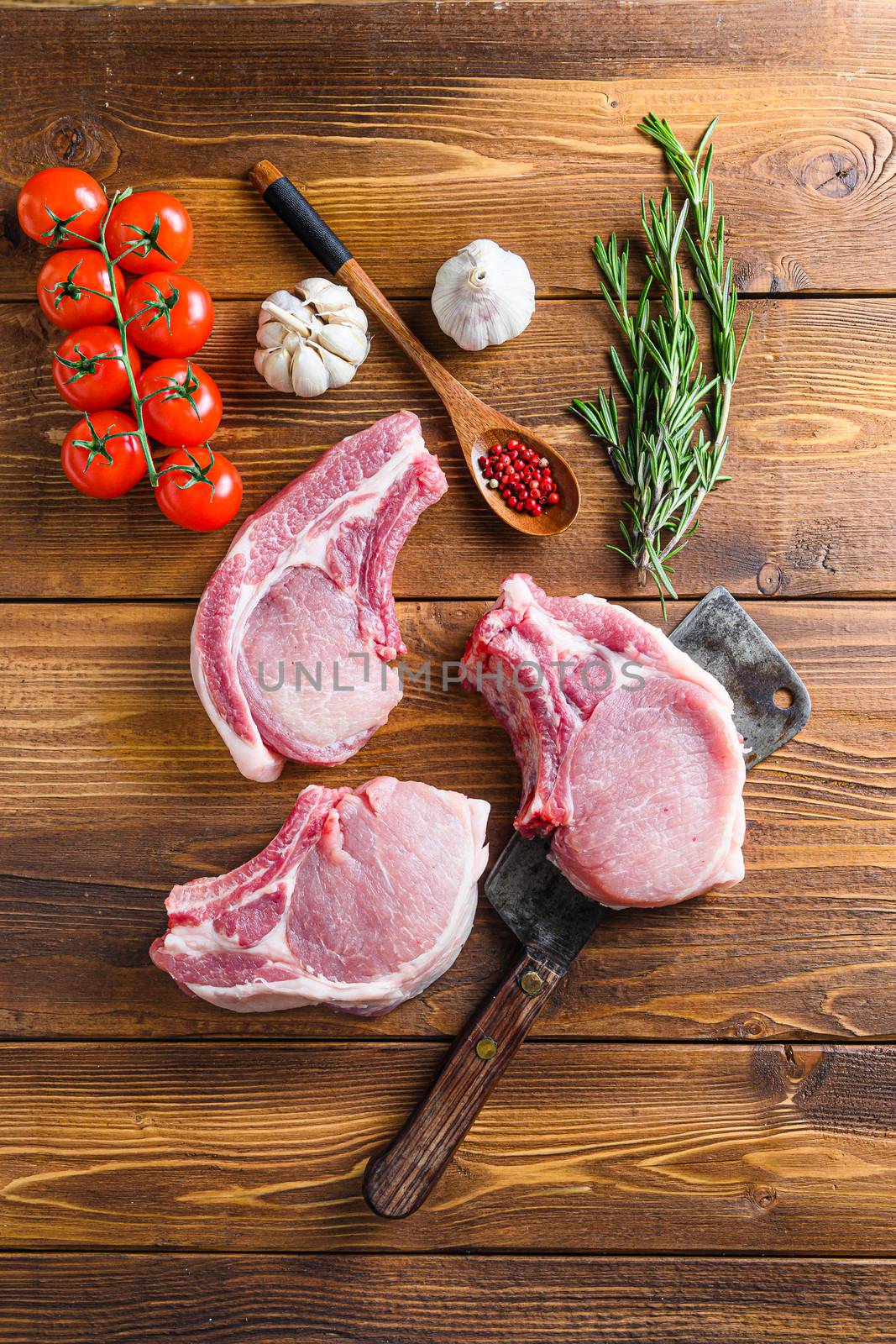 Raw pork meat chopes with herbs and spices with meat american cleaver on wooden background by Ilianesolenyi