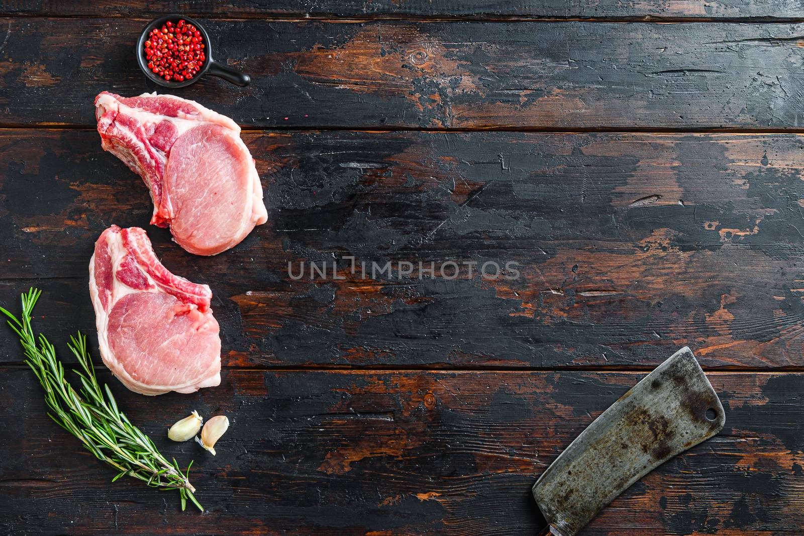 Raw pork meat chopes with herbs and spices with meat american cleaver on dark rustic wooden background side view space for text. by Ilianesolenyi