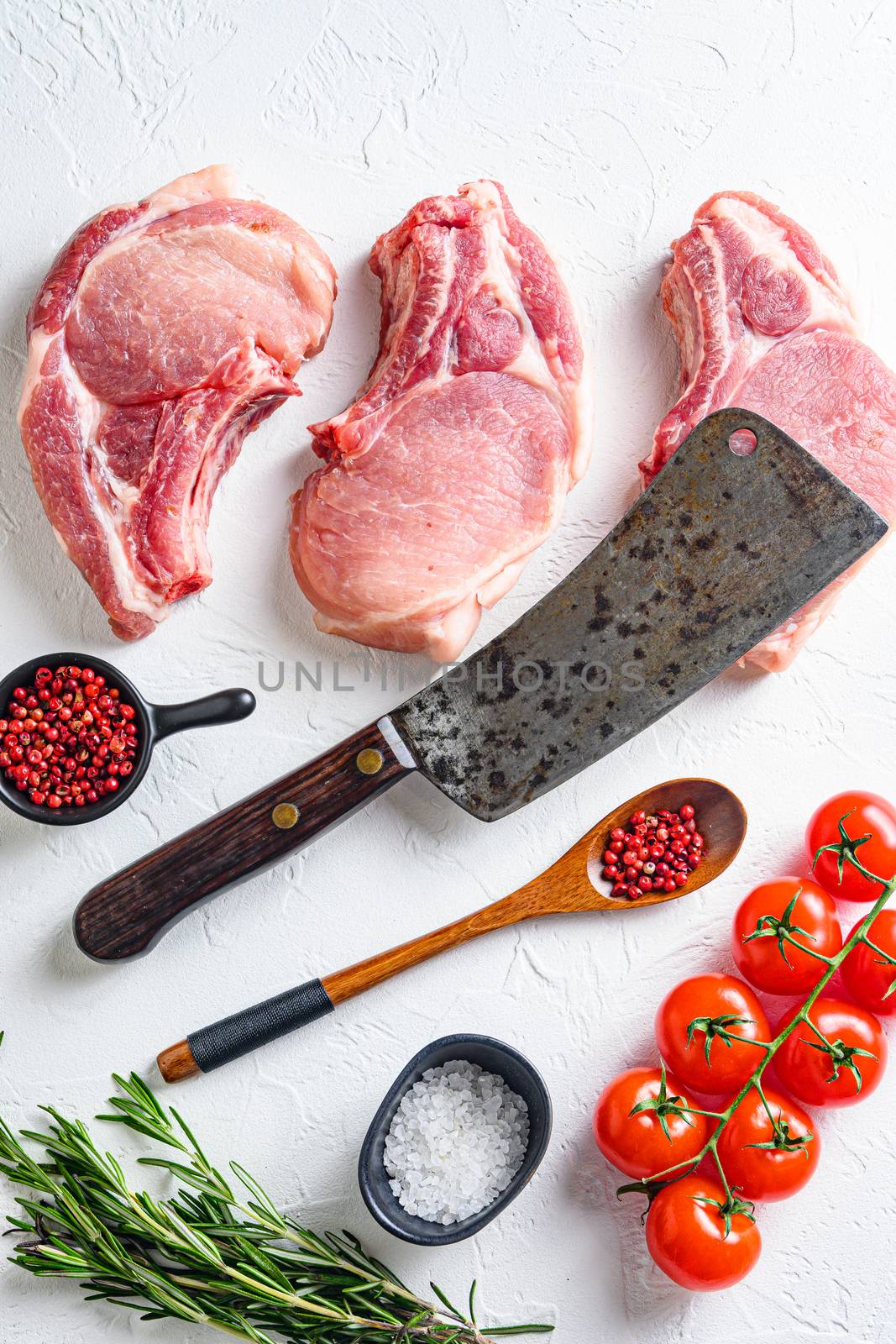 Set for bio grilling butcher cleaver over organic bio Raw pork chops , baking or frying, textured white background. vertical top view layflat by Ilianesolenyi