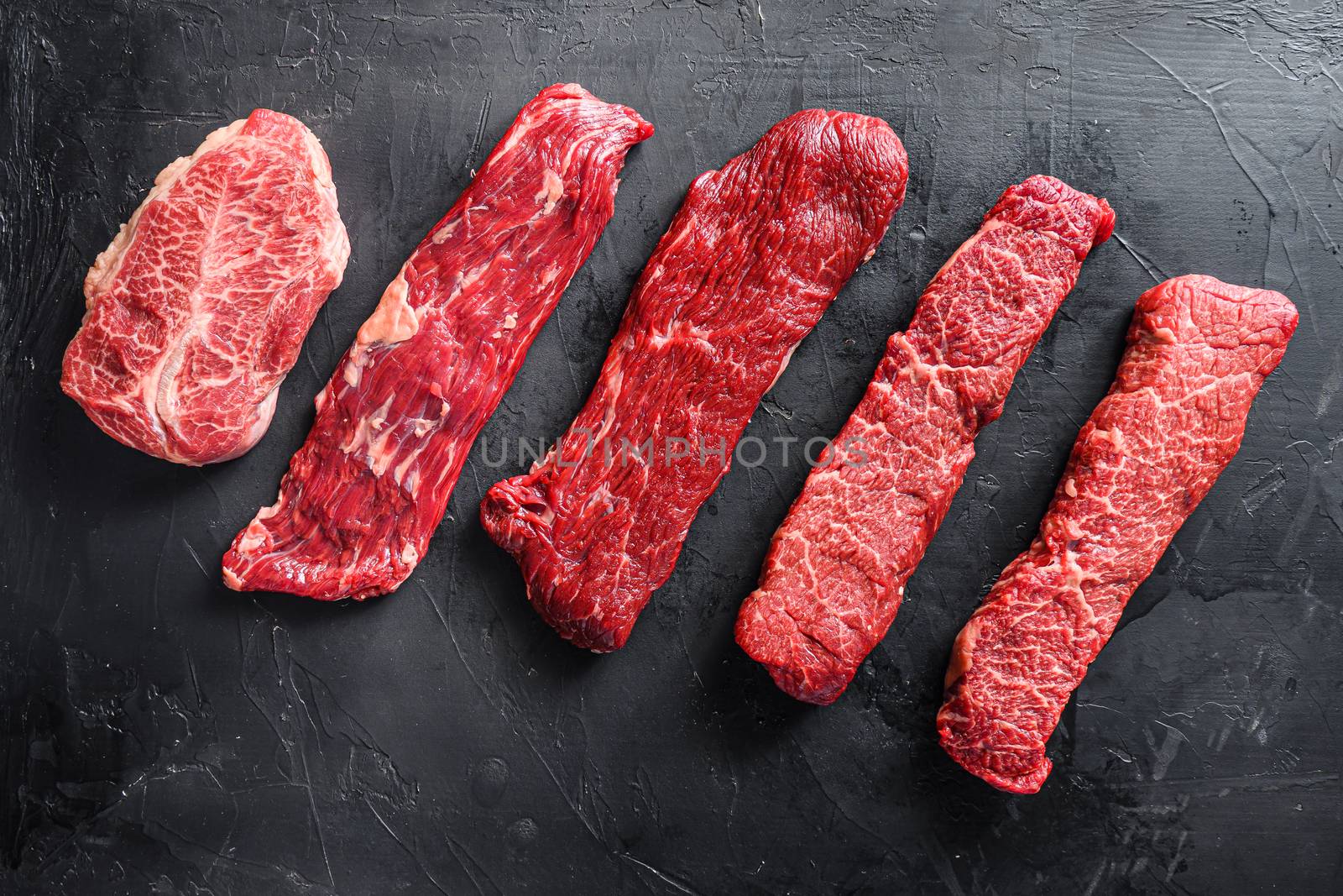 Raw, alternative beef steaks flap flank Steak, machete steak or skirt cut, Top blade or flat iron beef and tri tip, triangle roast with denver cut . Black stone background. Top view