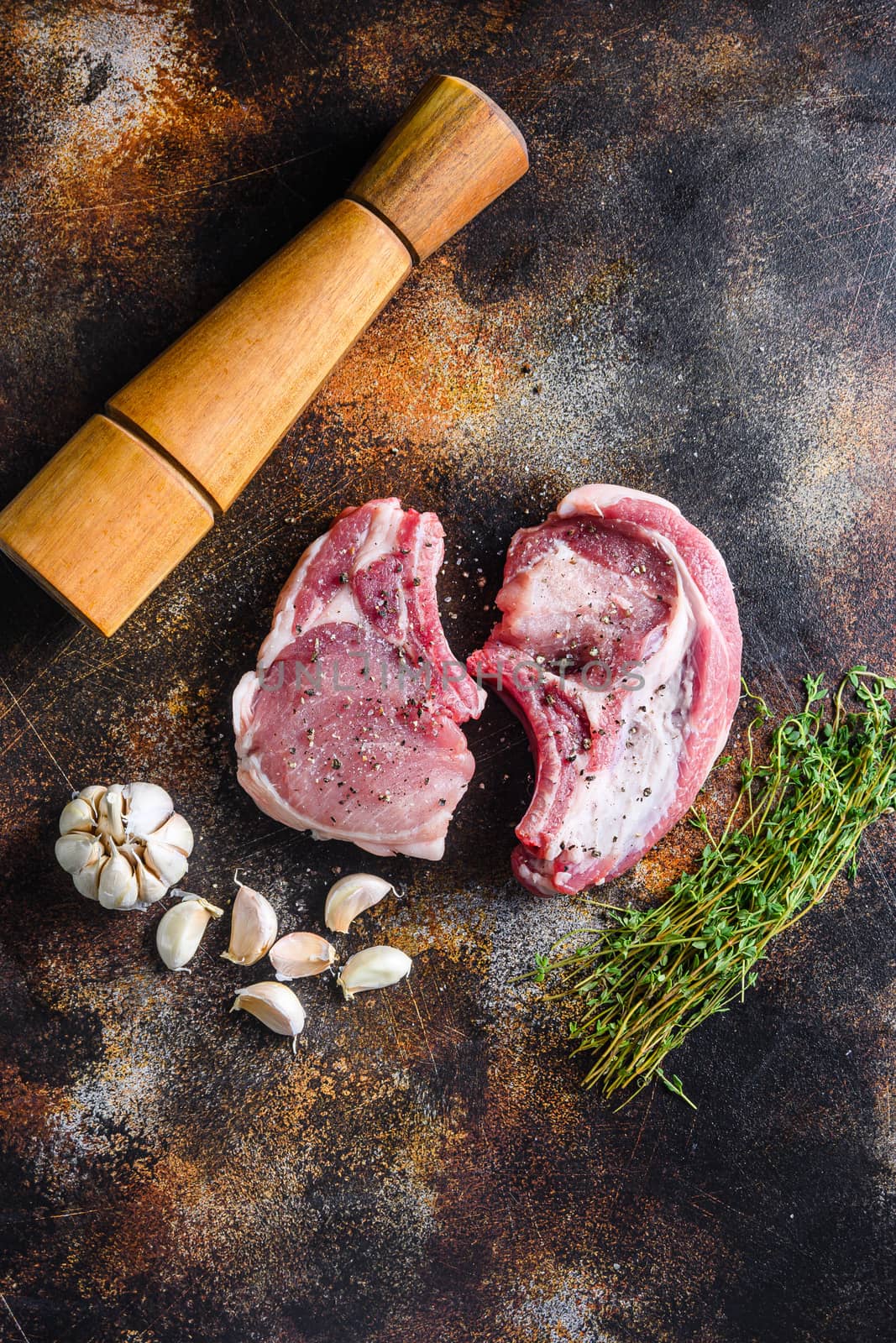 set organic pork chop steaks over dark background wood and rustic steel, close up top view vertical.