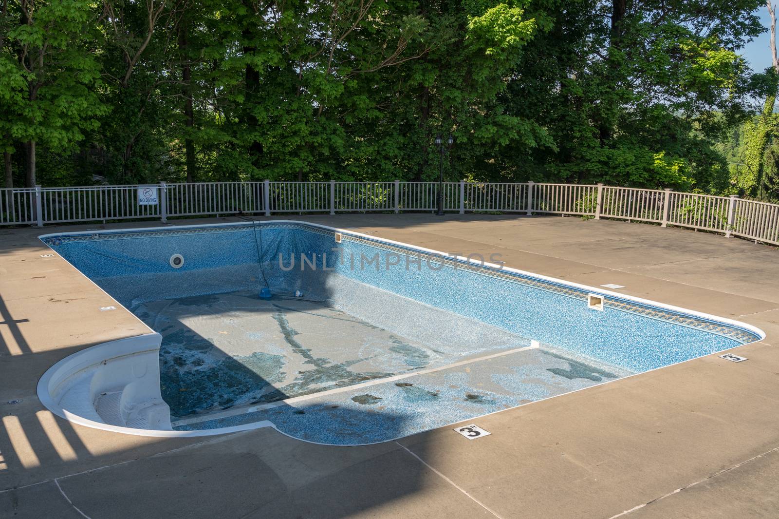 Empty in ground swimming pool ready for replacement of old vinyl lining or liner