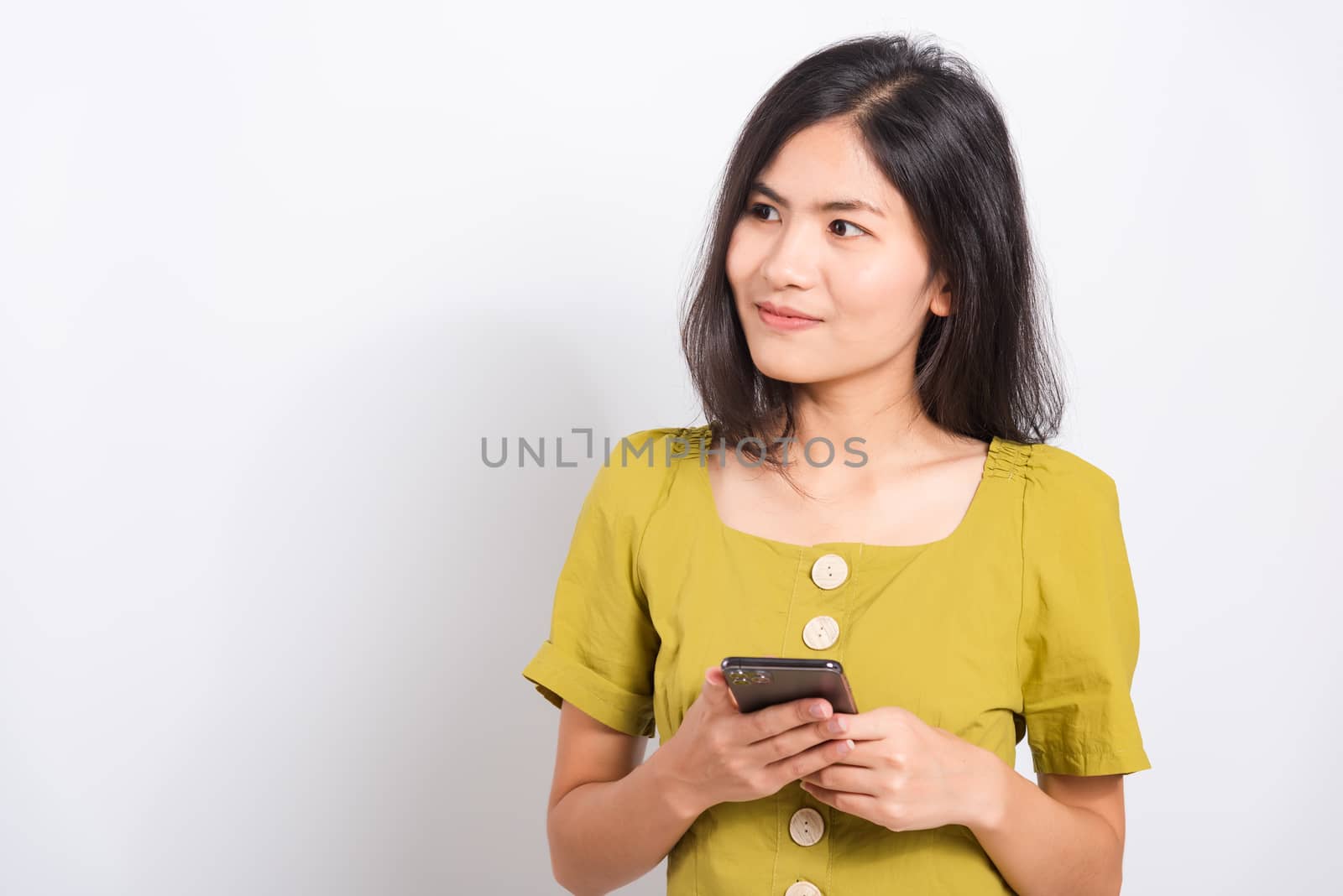 Portrait Asian beautiful happy young woman standing smile holding using mobile smart phone looking to side, shoot the photo in a studio on a white background, There was copy space