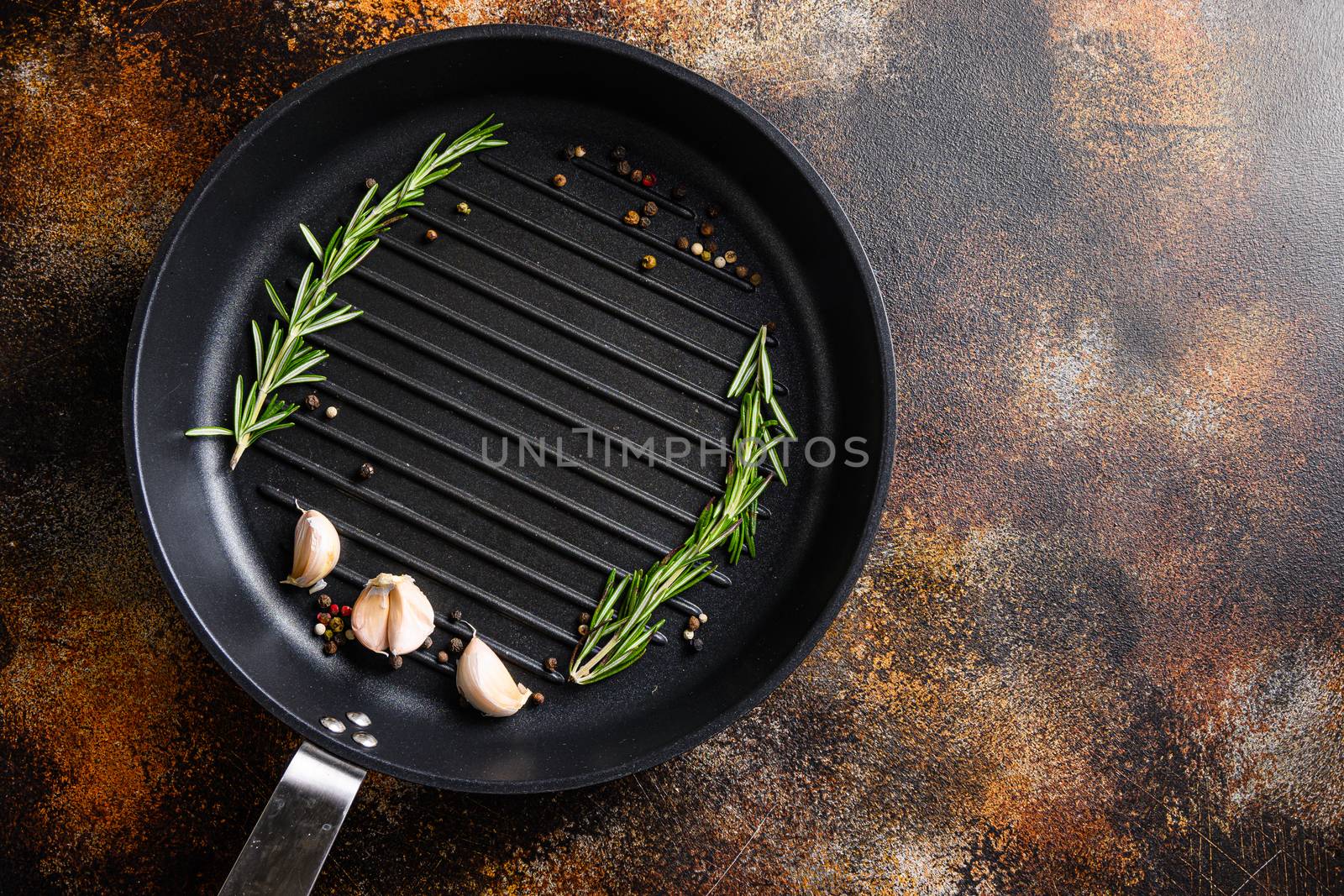 barbecue grill frying pan or skillet on rustic metall surface with herbs for cooking top view concept for text or objects by Ilianesolenyi