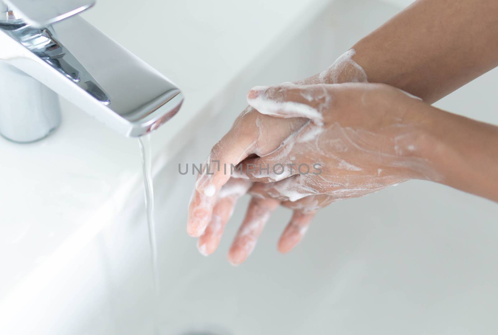 Closeup woman's hand washing with soap in bathroom, selective focus