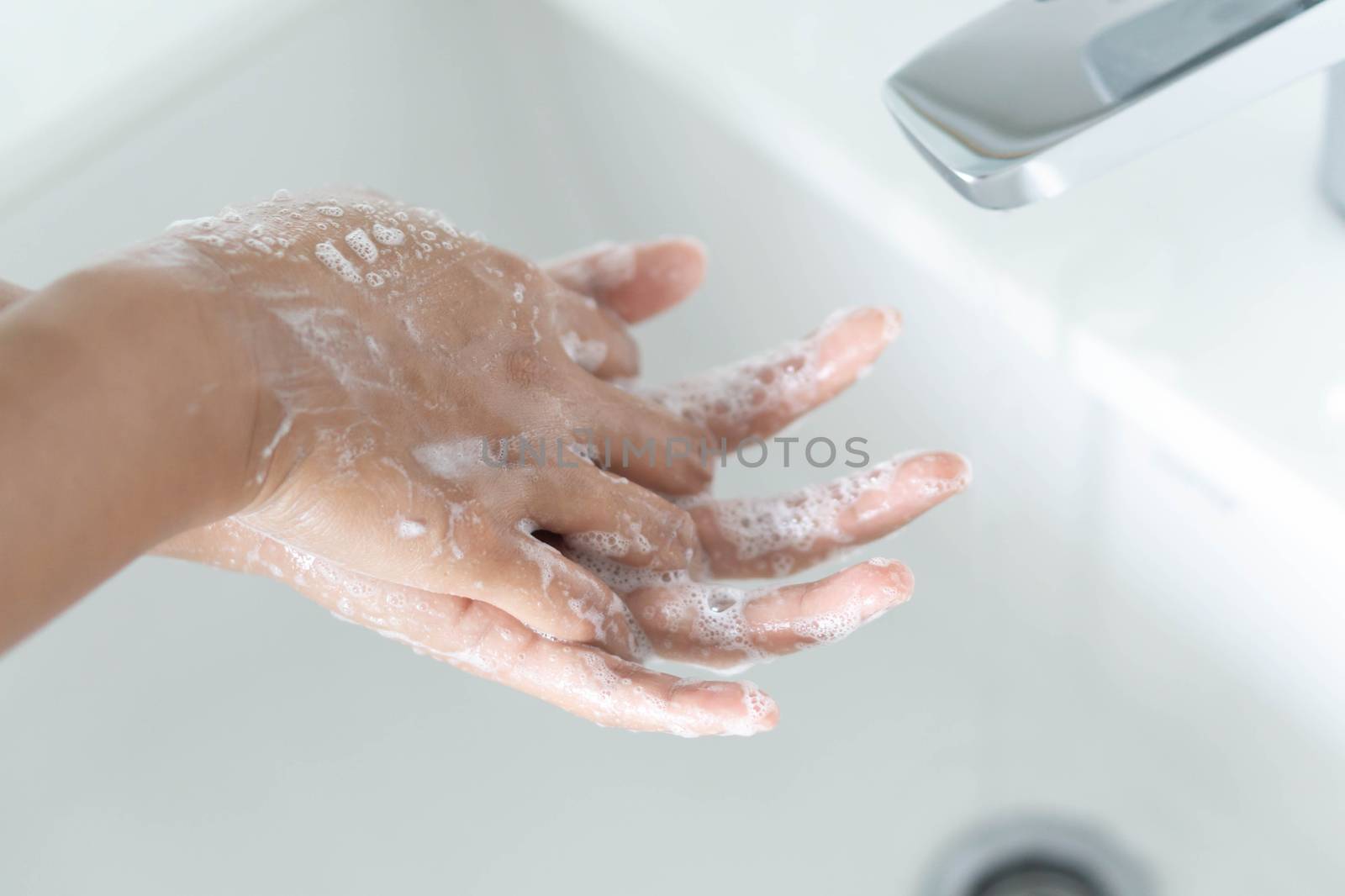 Closeup woman's hand washing with soap in bathroom, selective focus