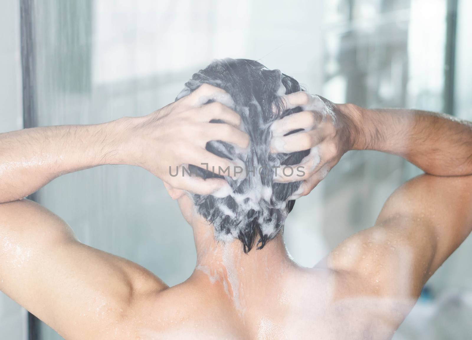 Closeup young man washing hair with with shampoo in the bathroom, vintage tone, selective focus