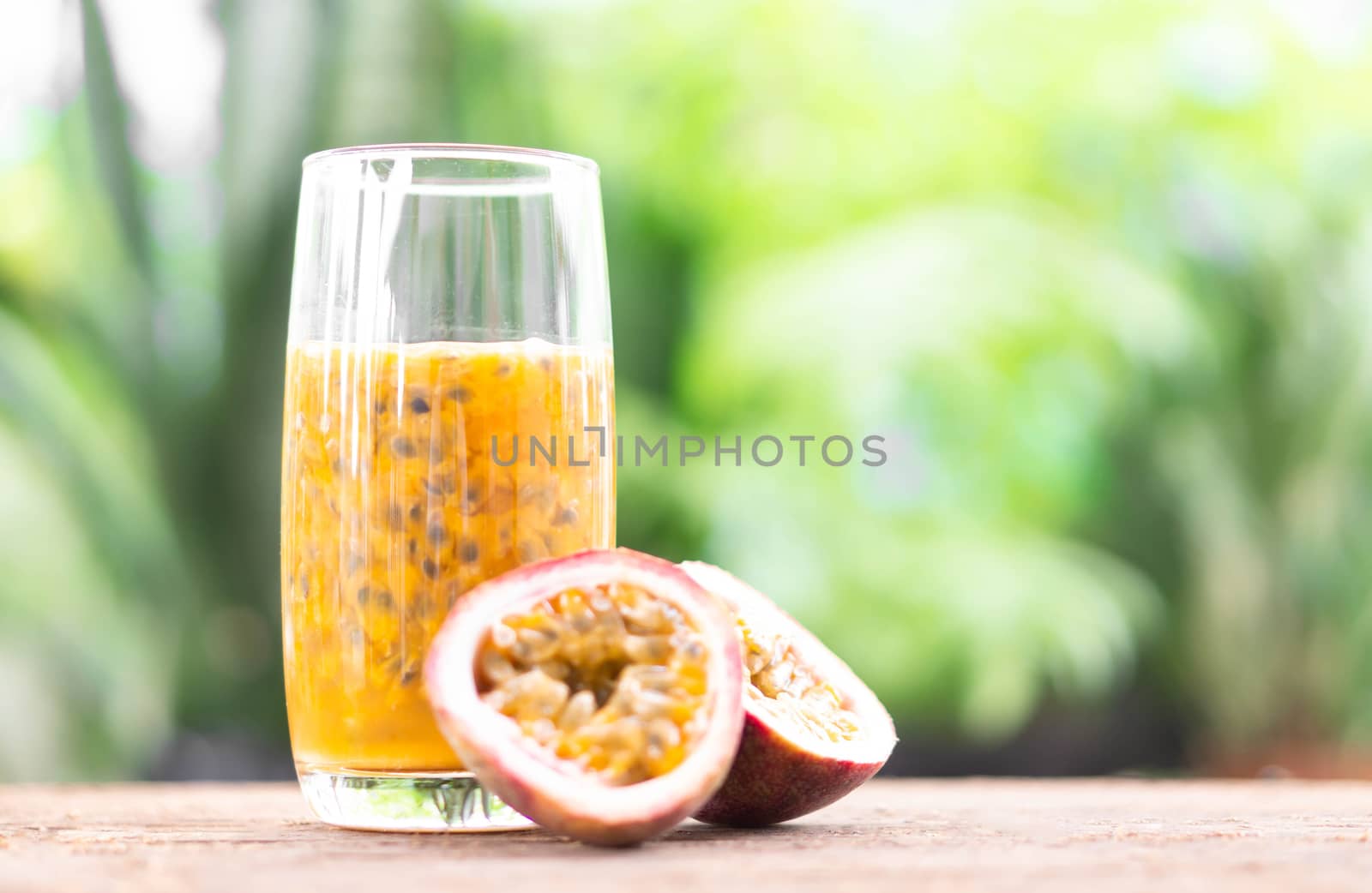 Glass of passion fruit juice wood table with green nature background, food healthy concept, selective focus