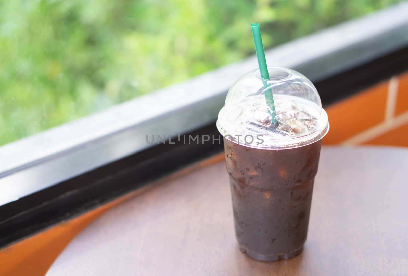 Close up glass of ice americano coffee on wood table in coffee shop, selective focus