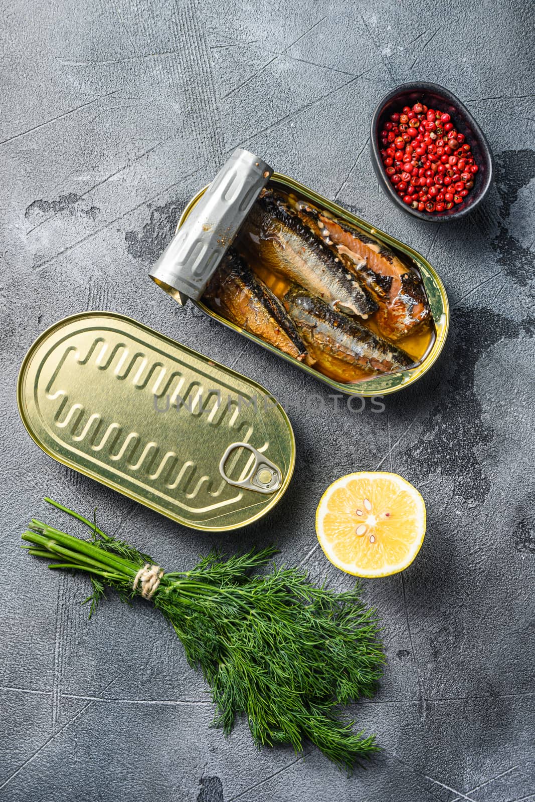 Canned saury, open and closed can with wfresh herbs, peppercorns, lemon, on grey concrete stone background top view by Ilianesolenyi