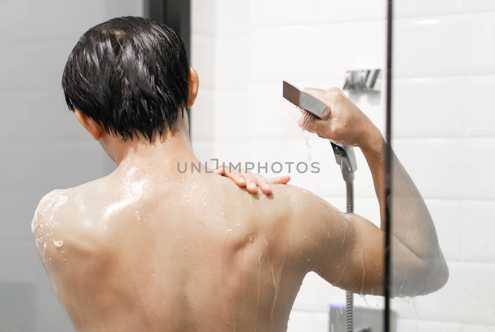 Closeup handsome asian man taking a shower in the bathroom, selective focus