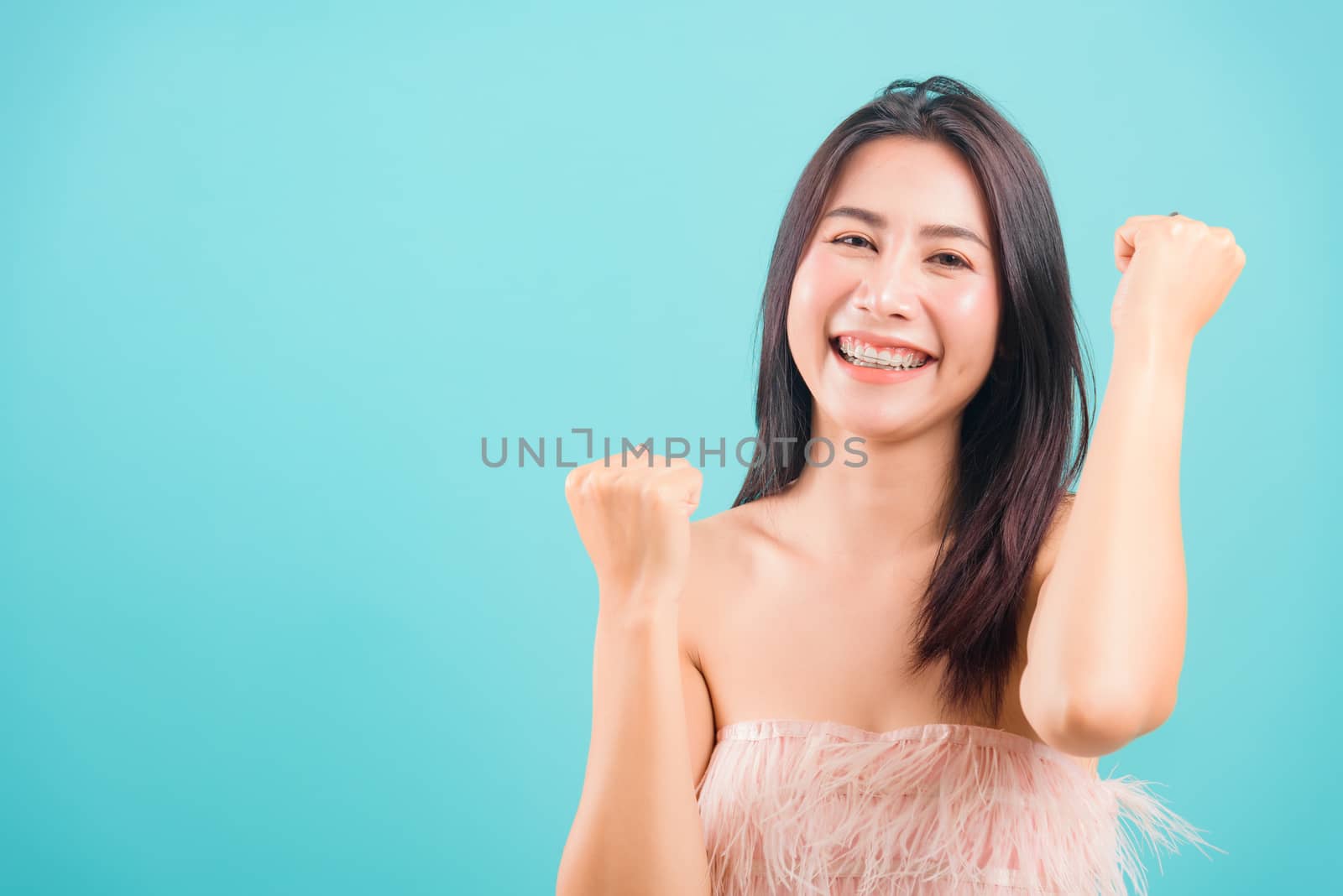 Smiling face Asian beautiful woman her celebrating success looking to camera on blue background, with copy space for text