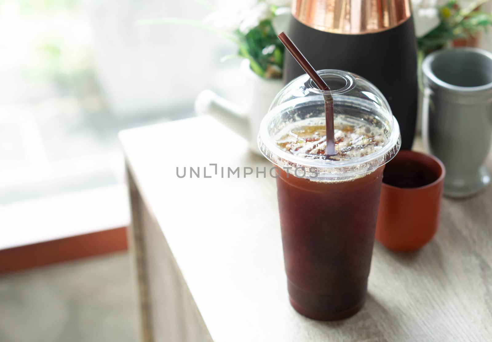 Close up ice of americano on wood table background with flower pot in coffee shop