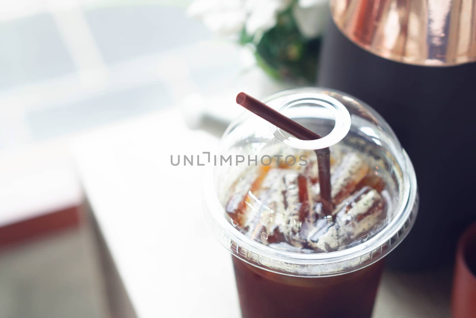 Close up ice of americano on wood table background with flower pot in coffee shop 