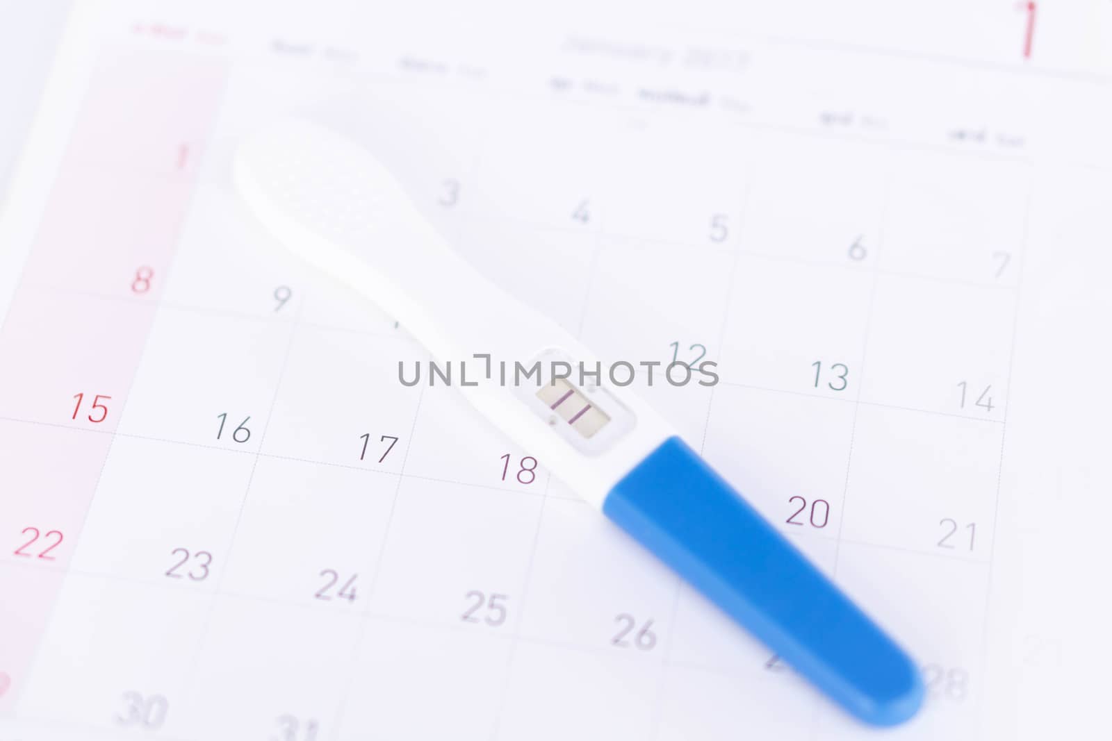 Closeup pregnancy test on calendar background, health care concept, selective focus