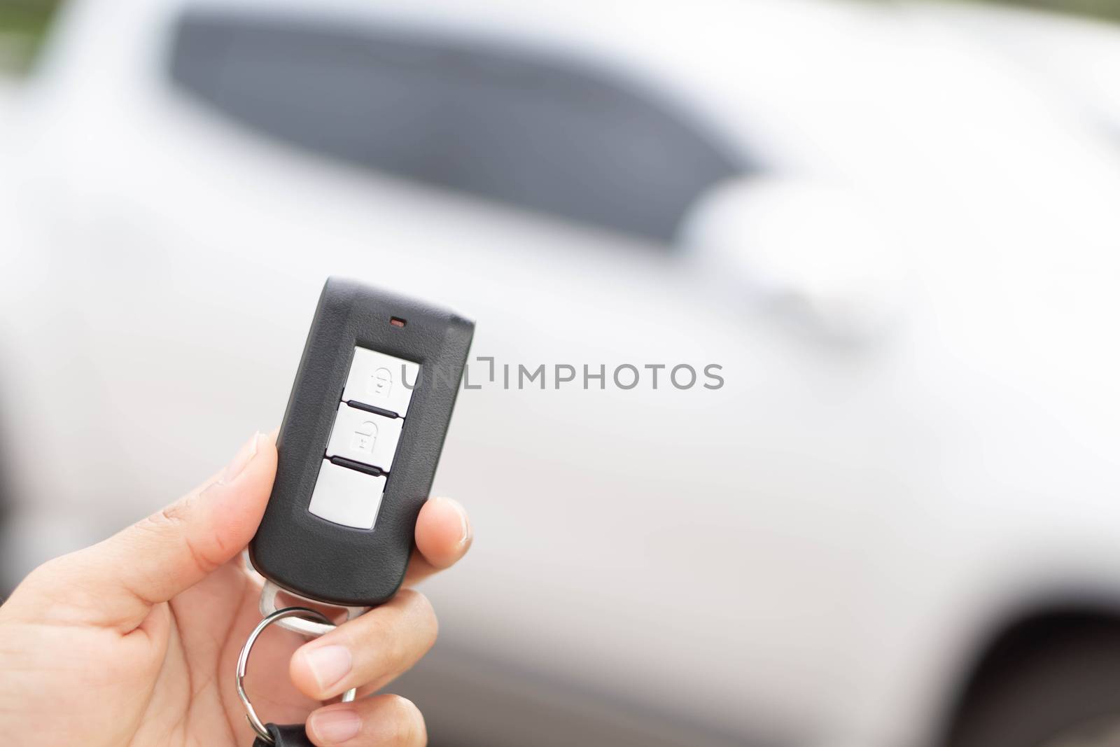 Closeup woman hand holding car key remote with car background