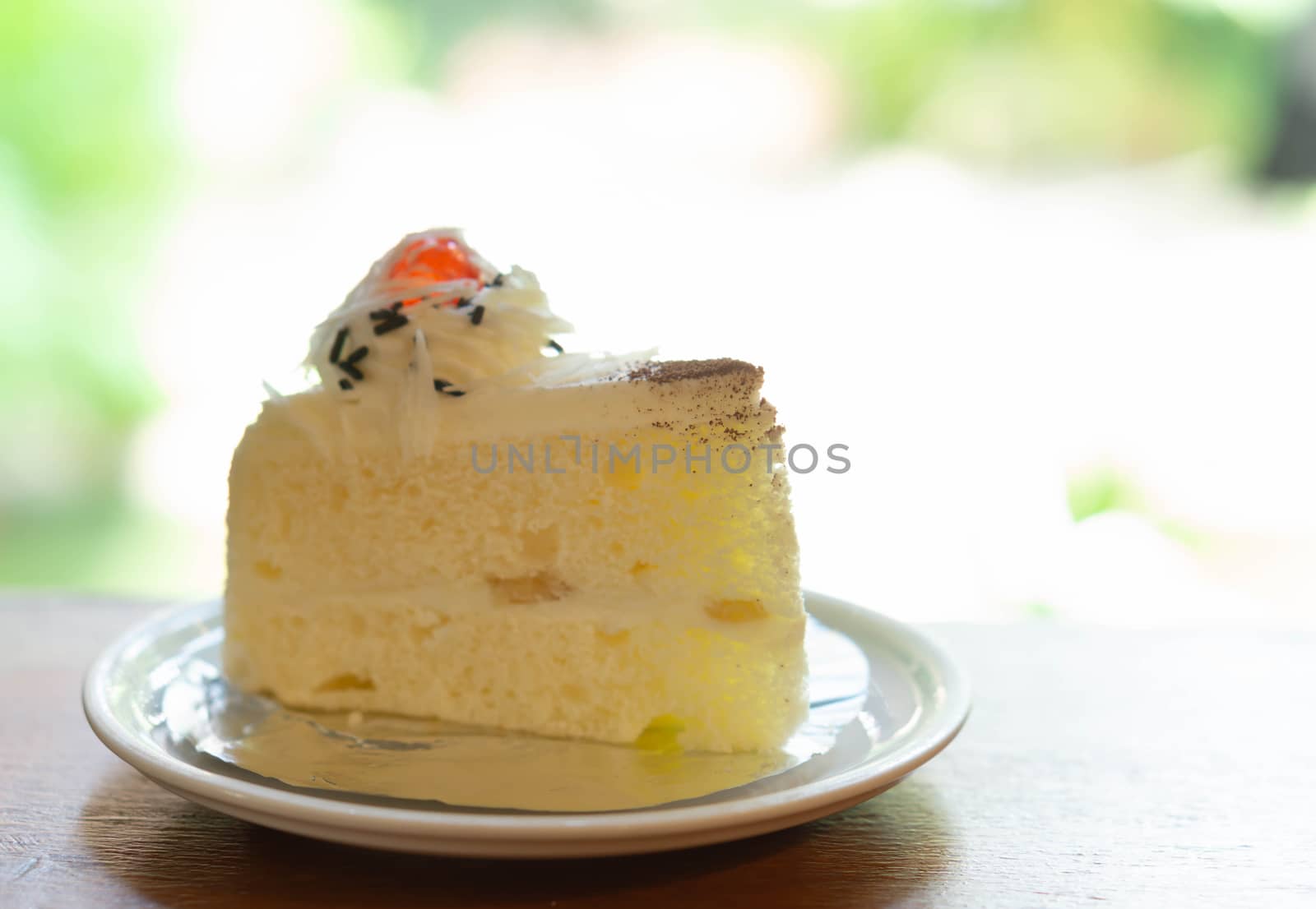 Closeup milk cake on wood table with green nature background, selective focus