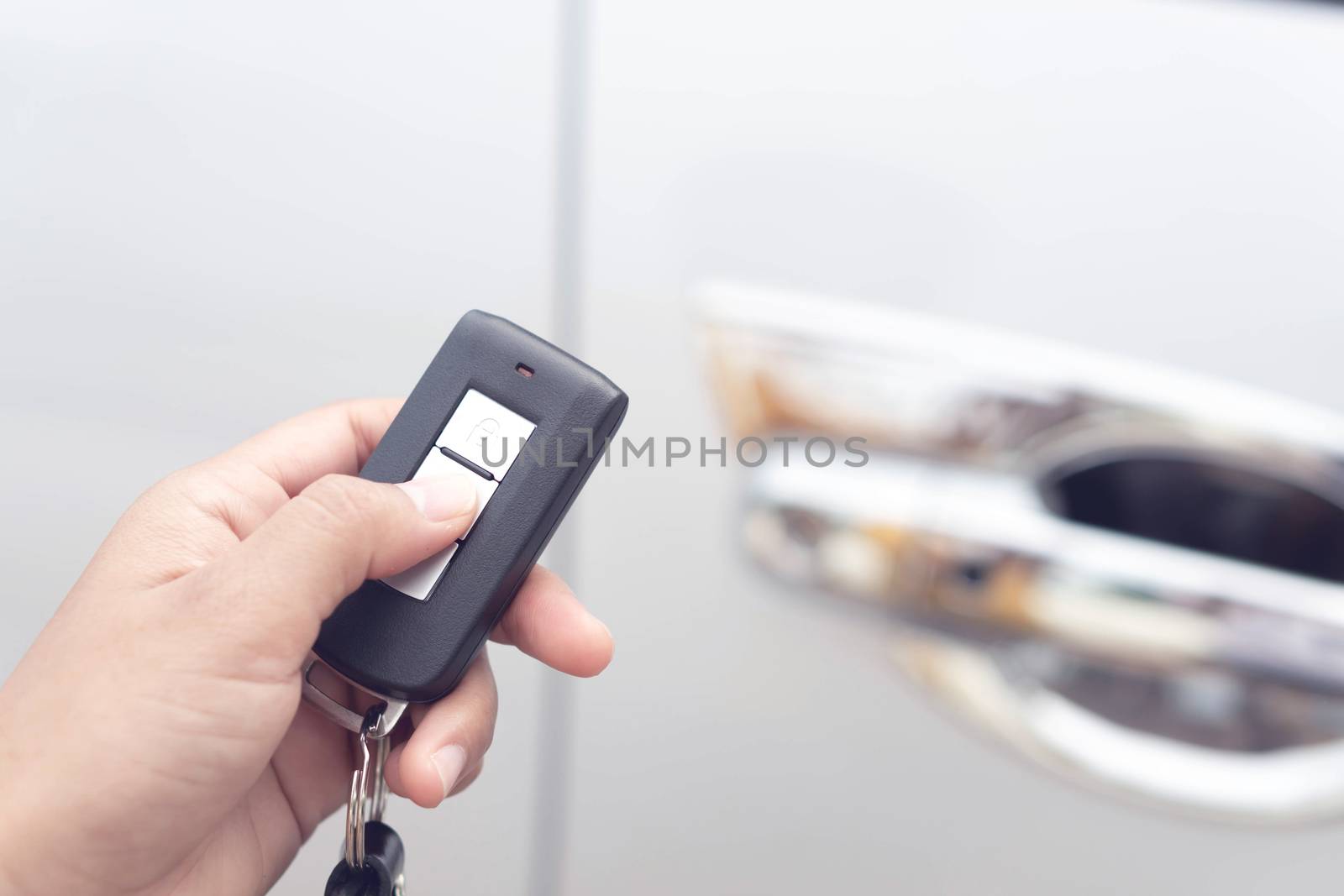 Closeup woman hand holding car key remote with car background by pt.pongsak@gmail.com