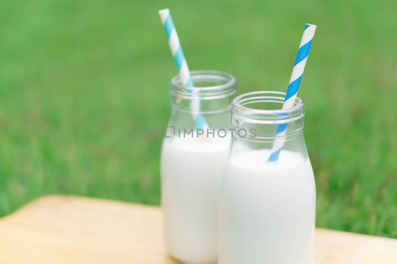 Closeup glass bottle of milk on green grass nature background, food healthy concept