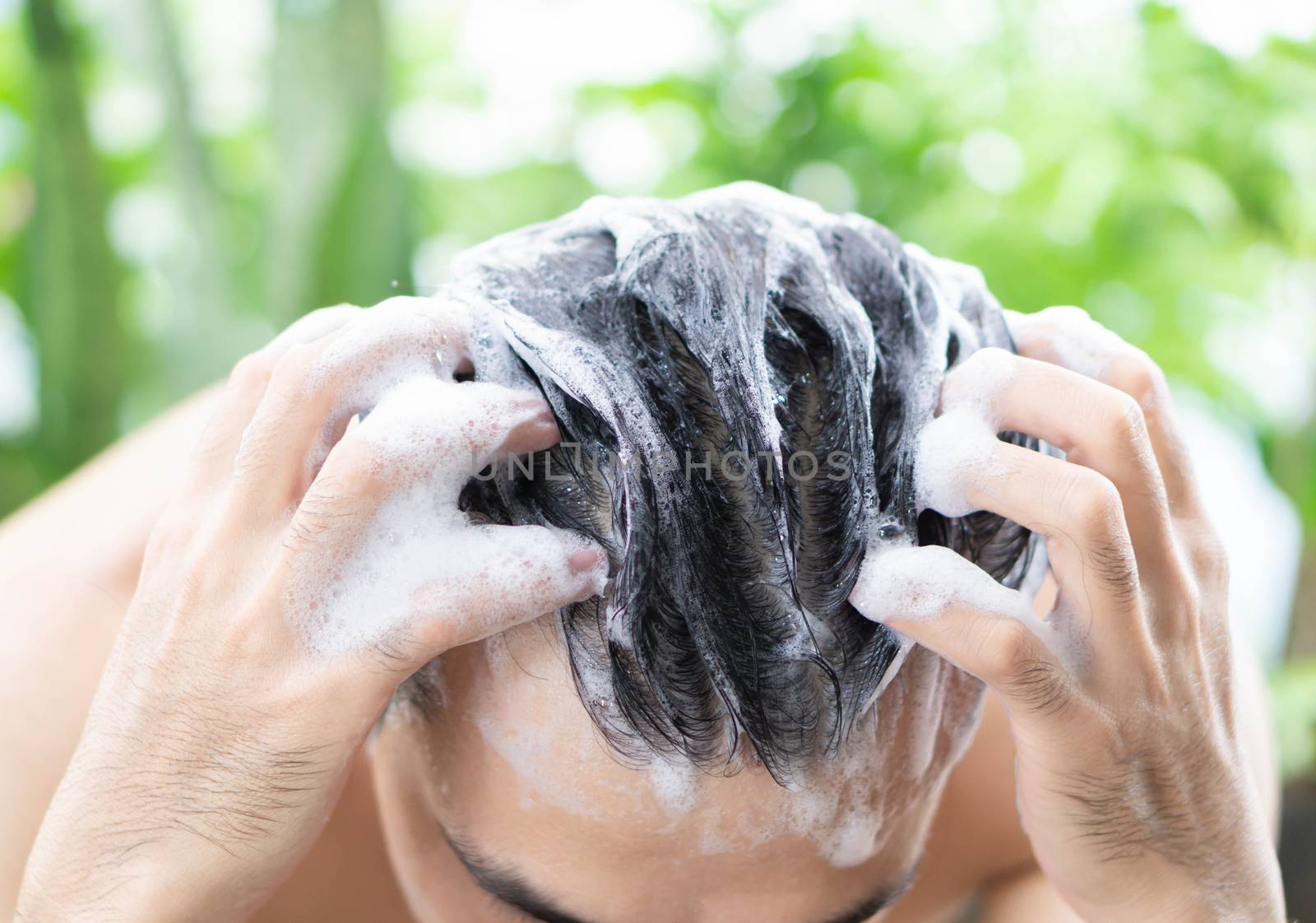 Closeup young man washing hair with shampoo outdoor, health care concept, selective focus
