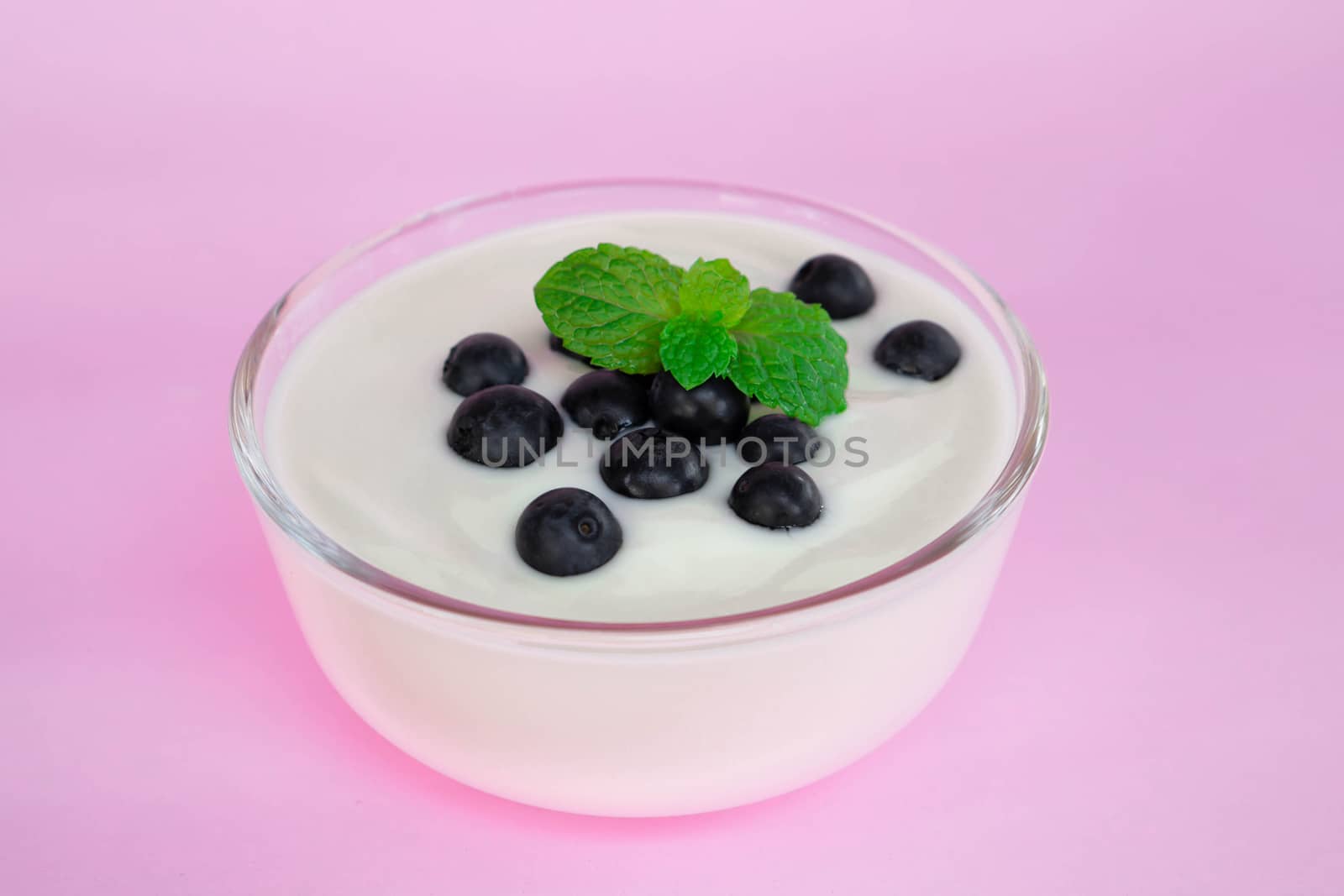 Close up yogurt with fresh blueberries  fruit in glass bowl  on pink background