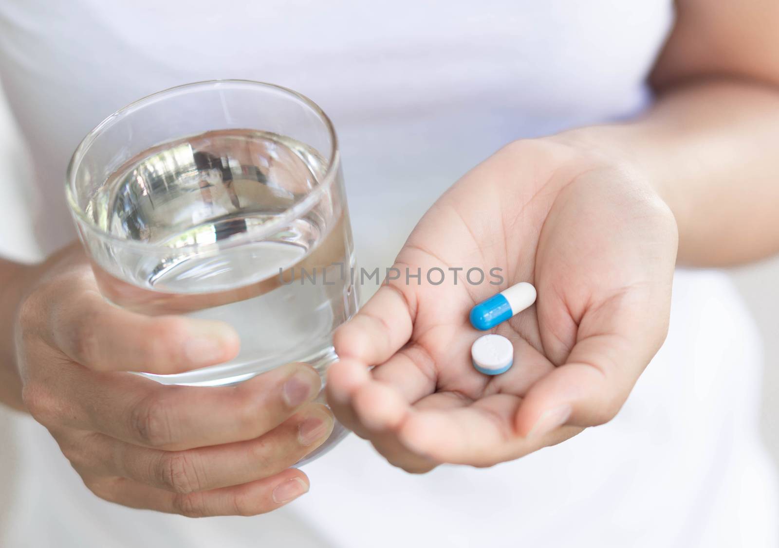 Closeup waman hand holding pills and glass of water, health care by pt.pongsak@gmail.com