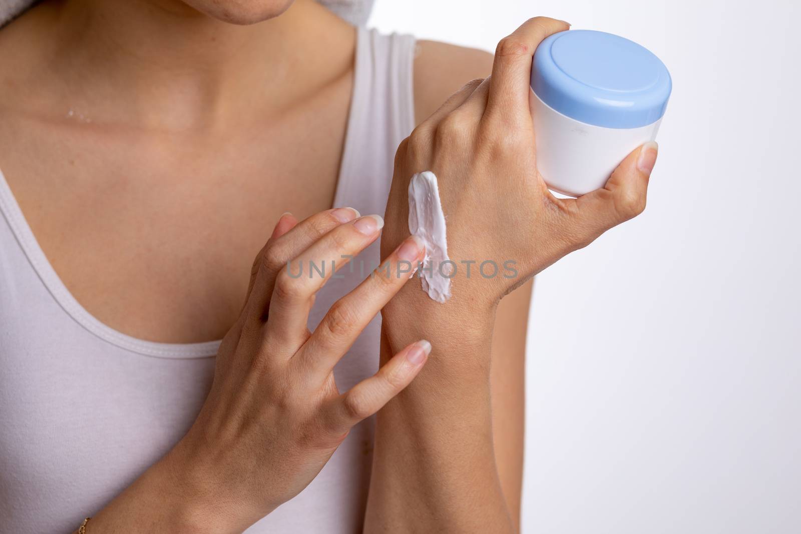 Young woman applying hand cream to protect and care skin, close up.