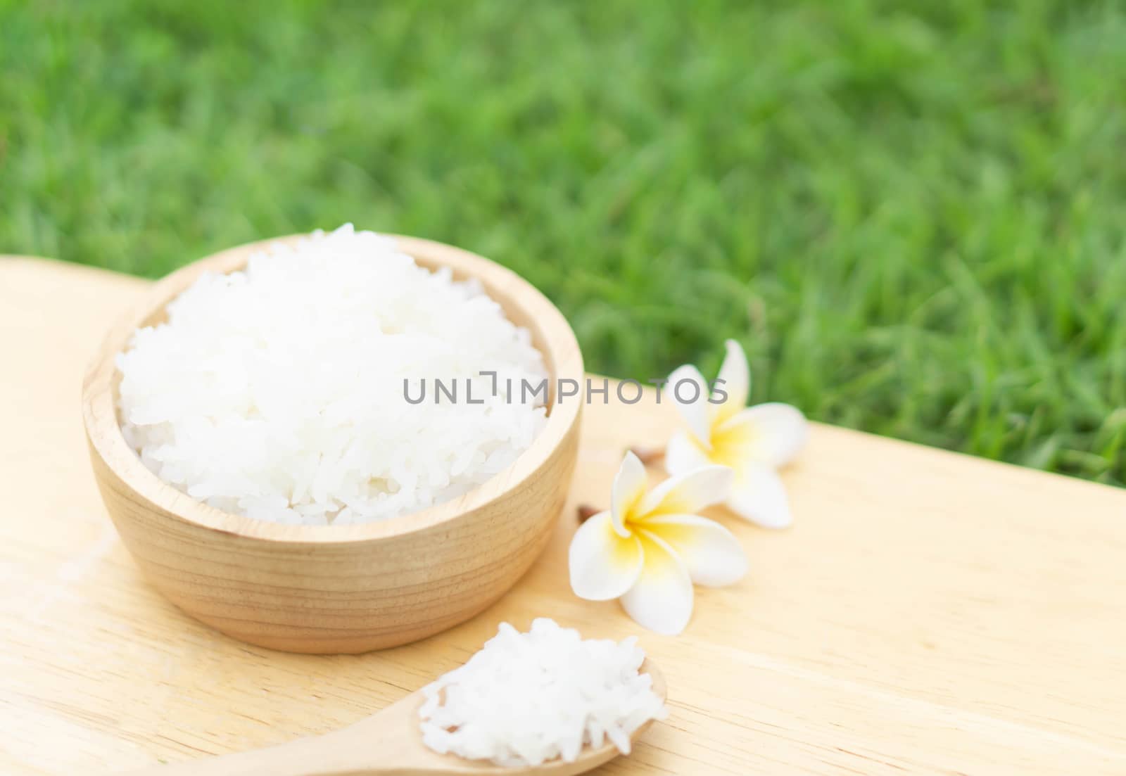 Close up white rice in wooden bowl with green nature background, healthy food, selective focus