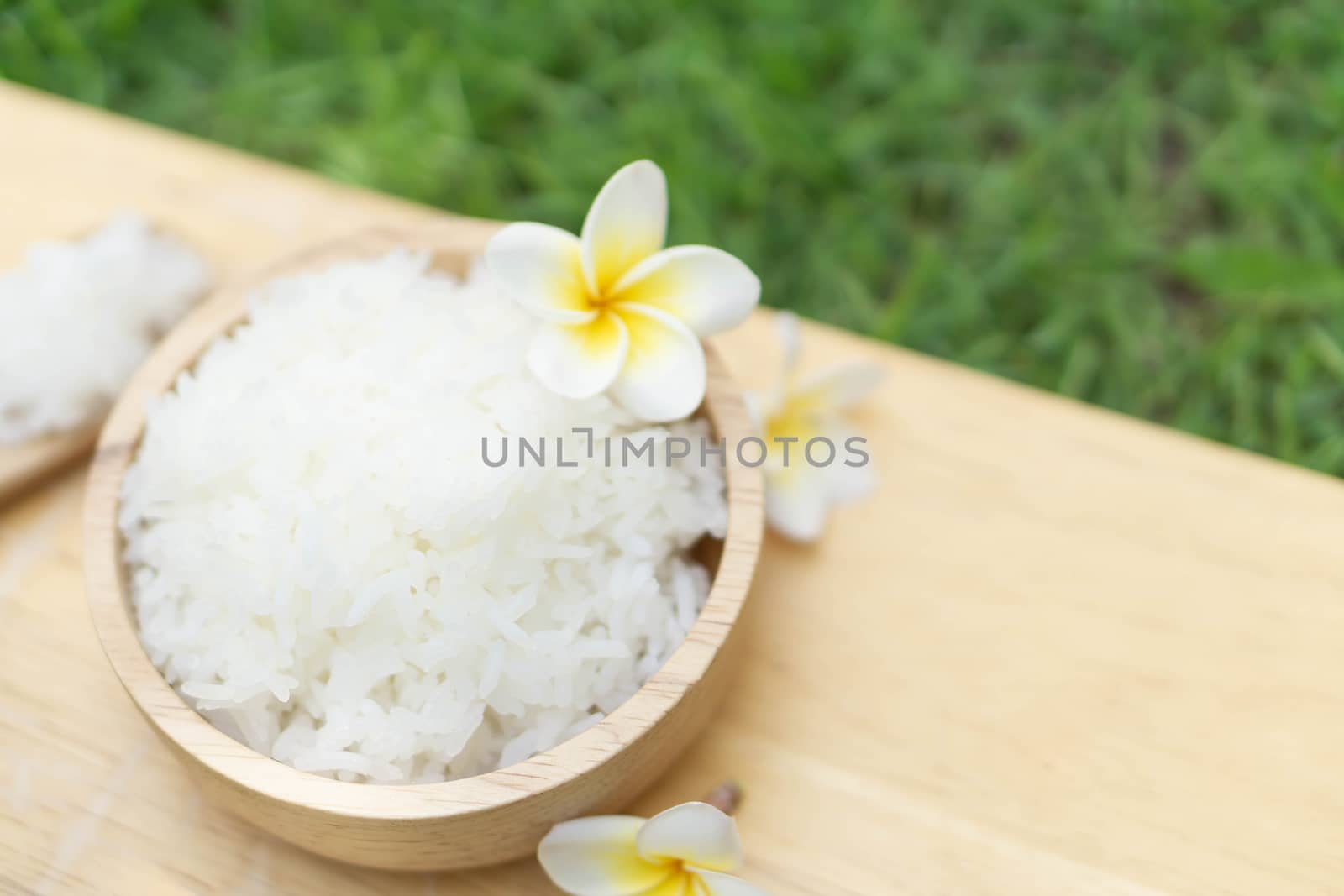 Close up white rice in wooden bowl with green nature background, healthy food, selective focus