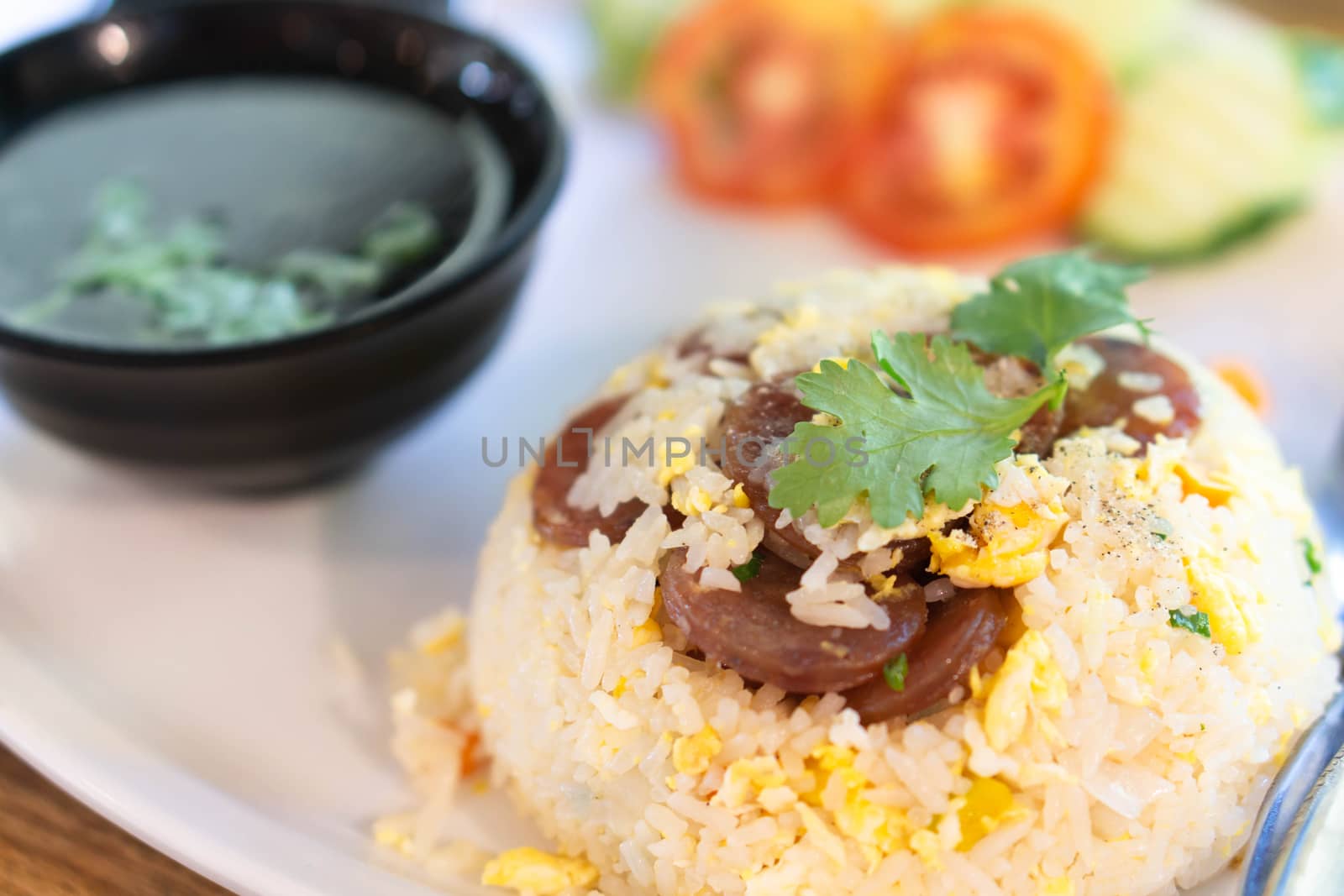 Closeup fired rice with sausage and vegetable in plate on wood table