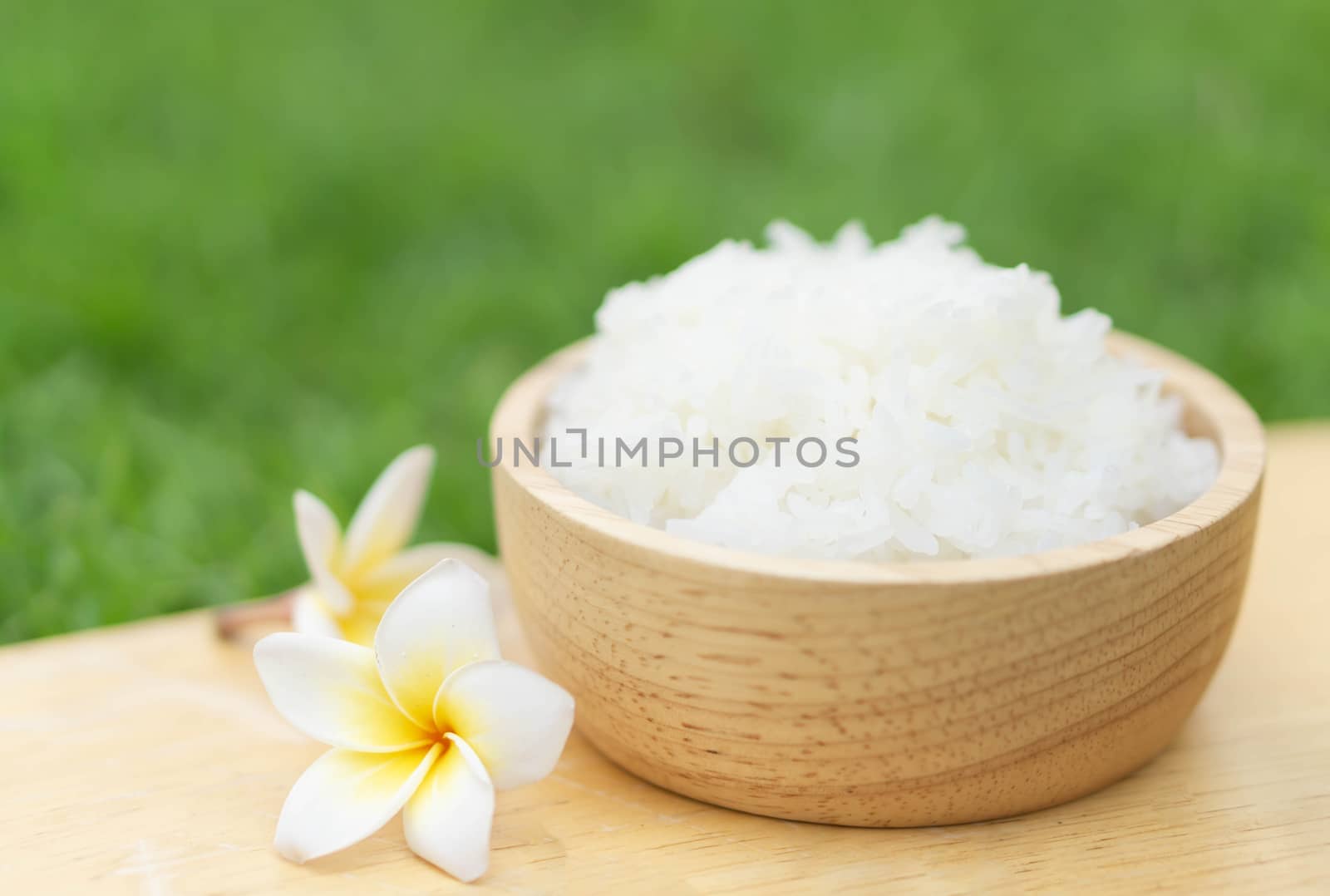 Close up white rice in wooden bowl with green nature background, healthy food, selective focus