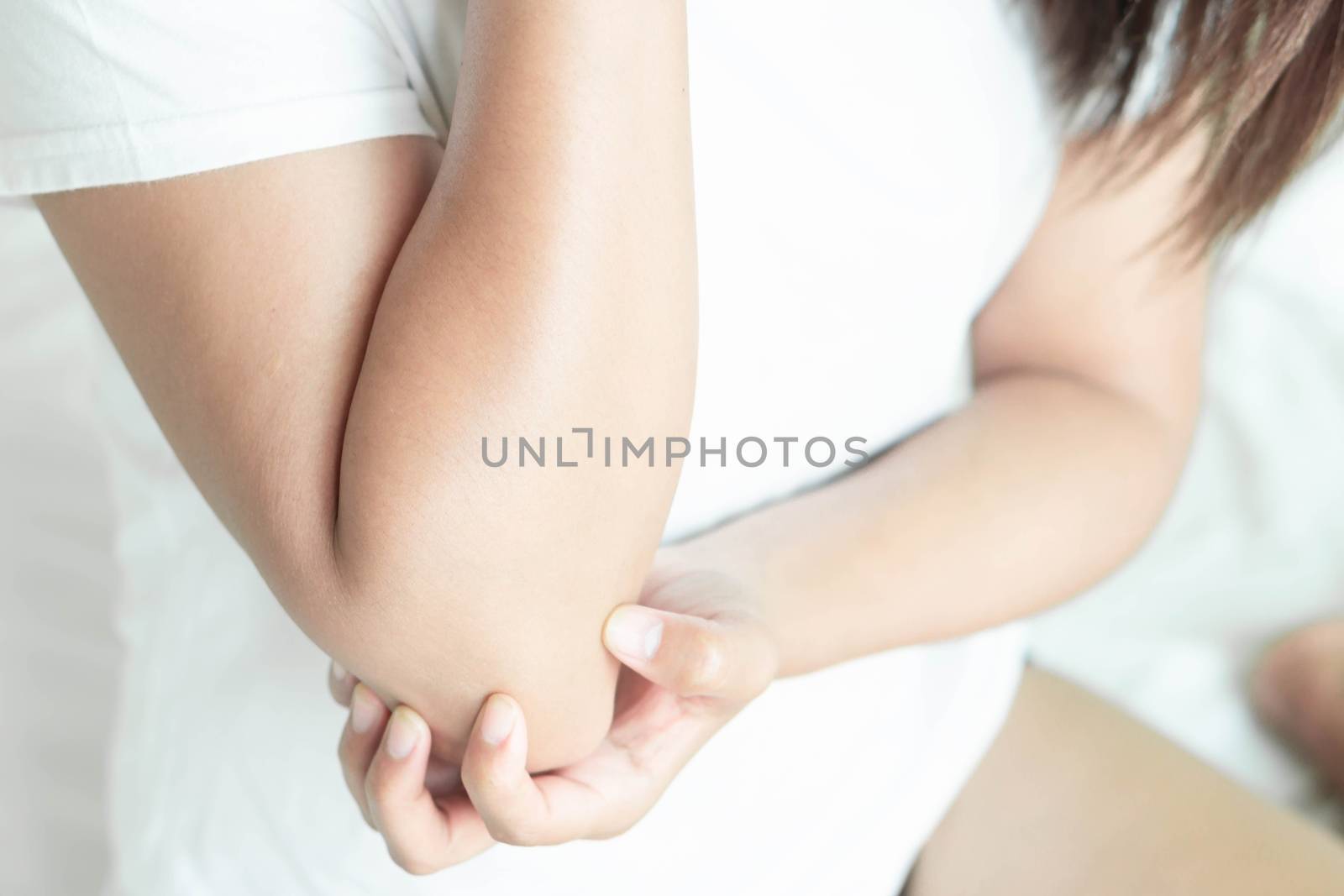 Closeup woman hand holding elbow with pain lying on bed, health care and medical concept