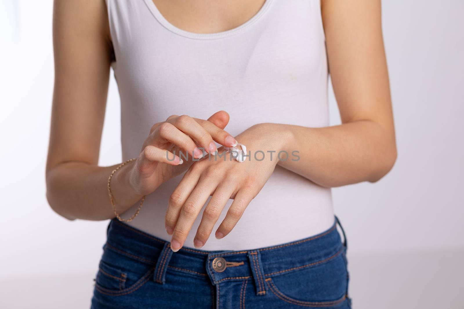 Young woman applying hand cream to protect and care skin, close up.