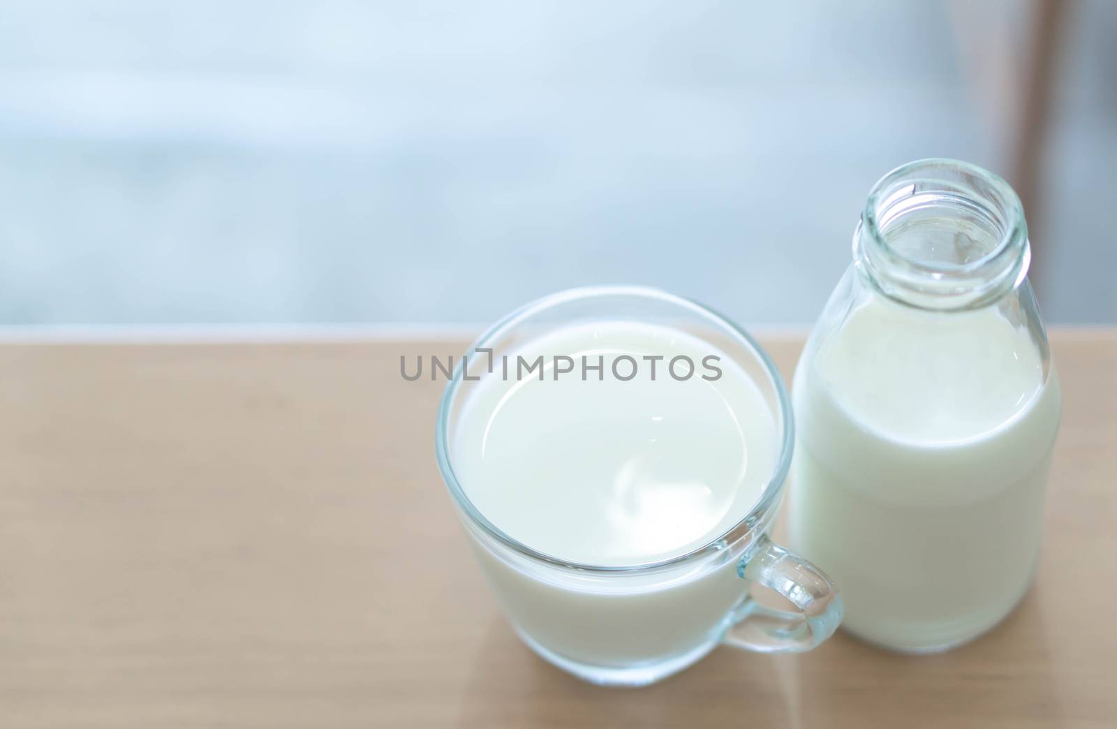 Closeup bottle of millk on wood table background with over light from out door for healthy drink concept and copy space for text advertise, selective and soft focus