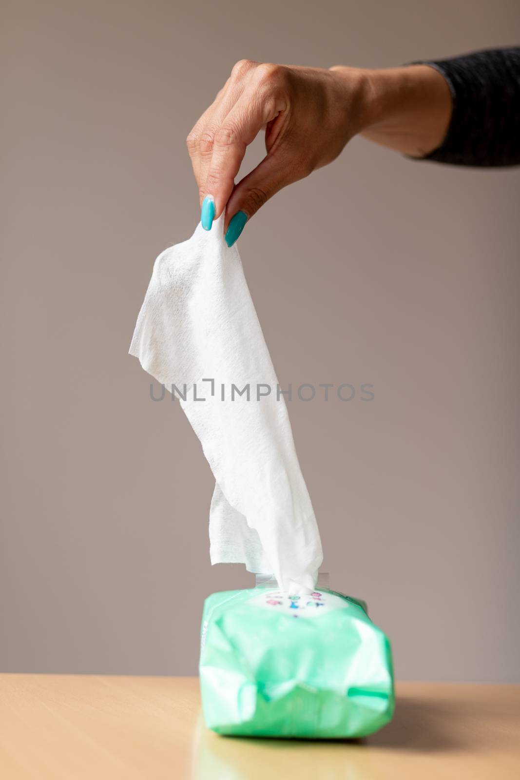 Old woman hand with turquoise nails taking the wet wipe to clean skin or surface stock photo