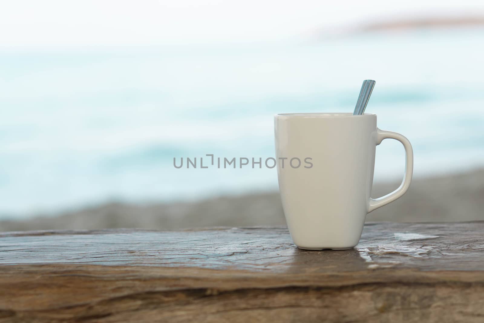 Closeup white ceramic glass of coffee on wood table with sea water and beach background by pt.pongsak@gmail.com