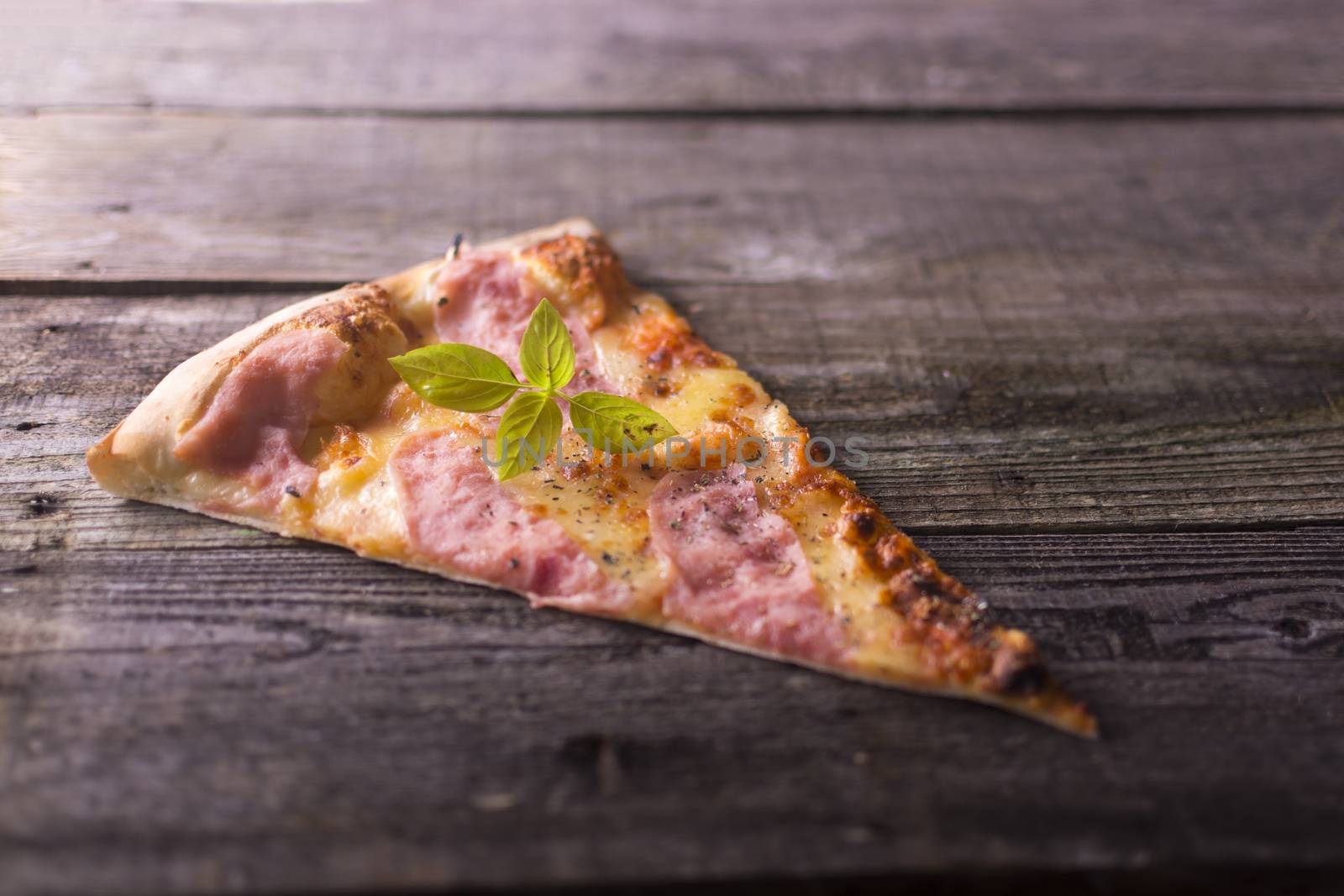 Piece of Basil on hot pizza, wooden background by adamr