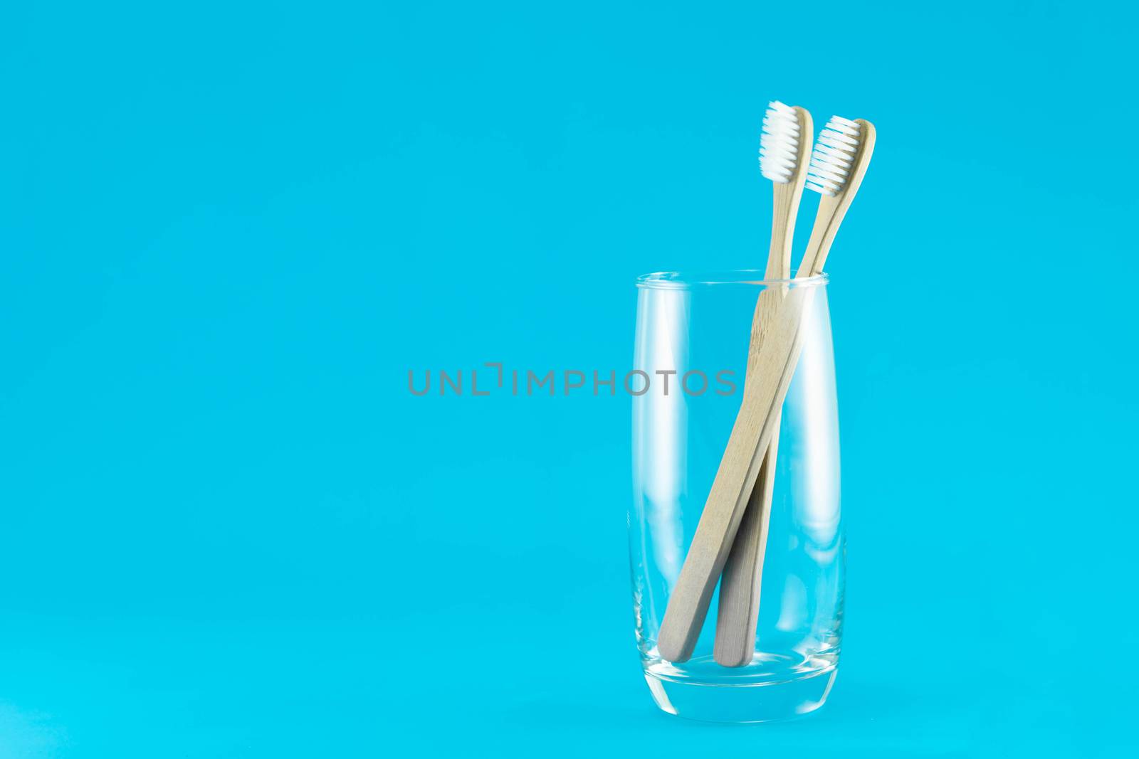 Wooden toothbrush in glass with blue background, selective focus