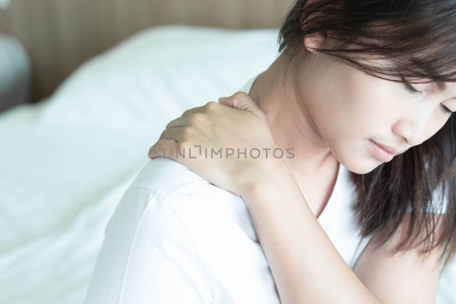 Closeup woman hand holding shoulder with pain on bed, health care and medical concept