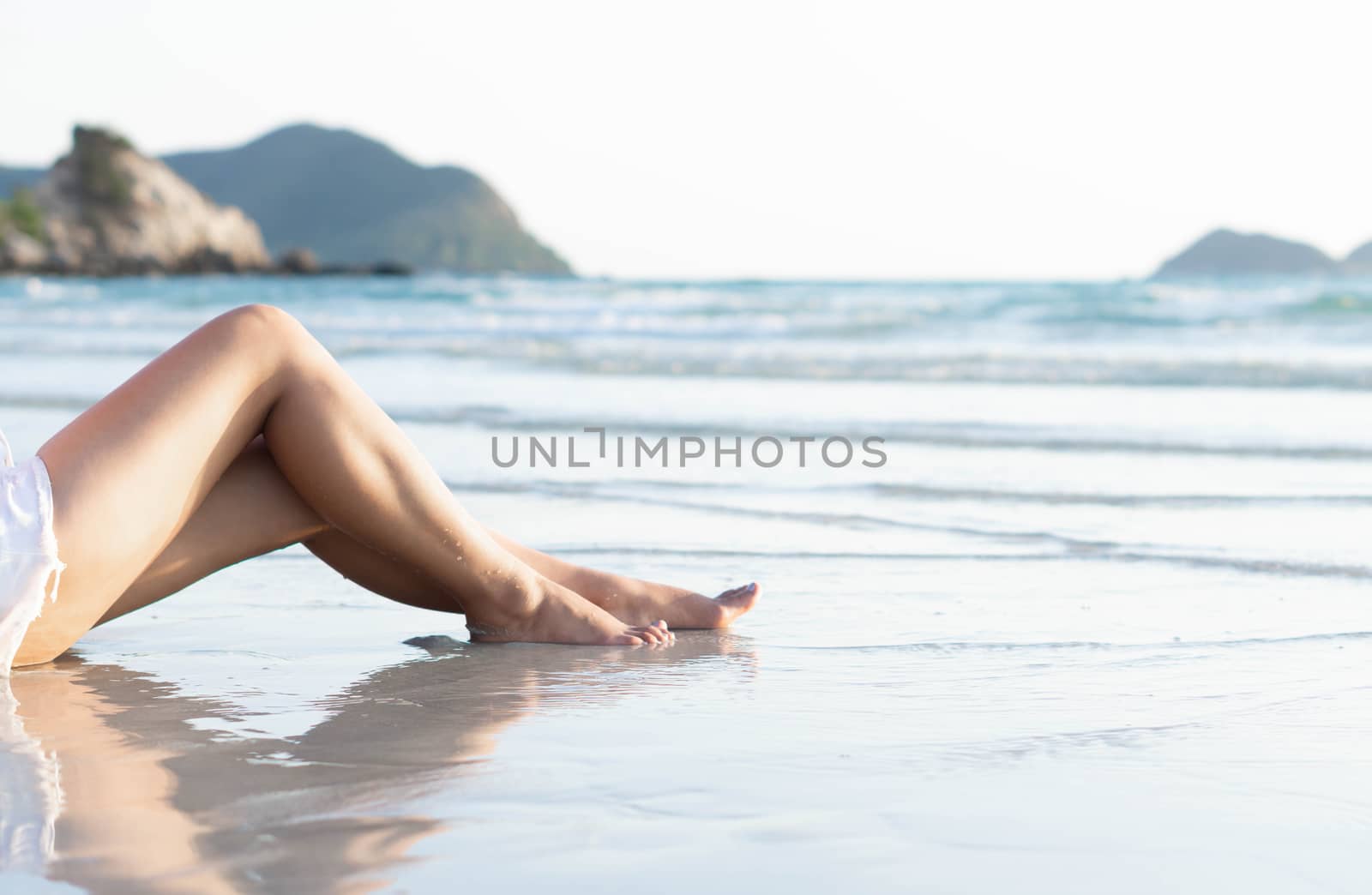 Beautiful woman's legs relaxing on the beach with light of sunse by pt.pongsak@gmail.com