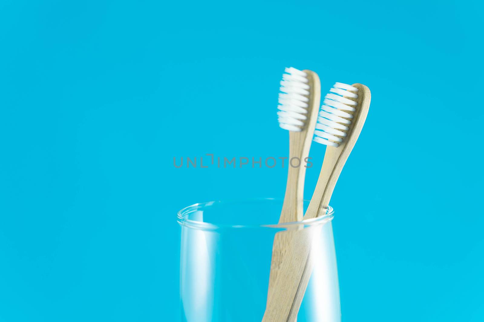 Close up wooden toothbrush in glass with blue background, selective focus