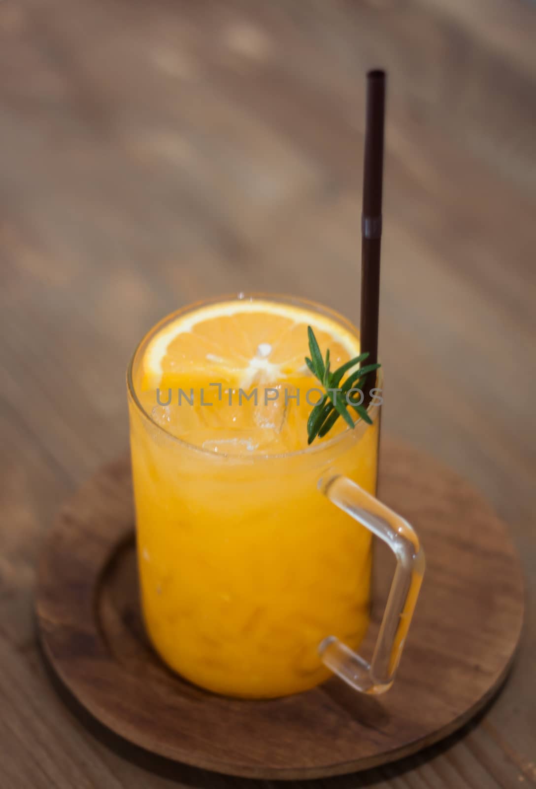 Glass of fresh orange juice with slice on wooden table