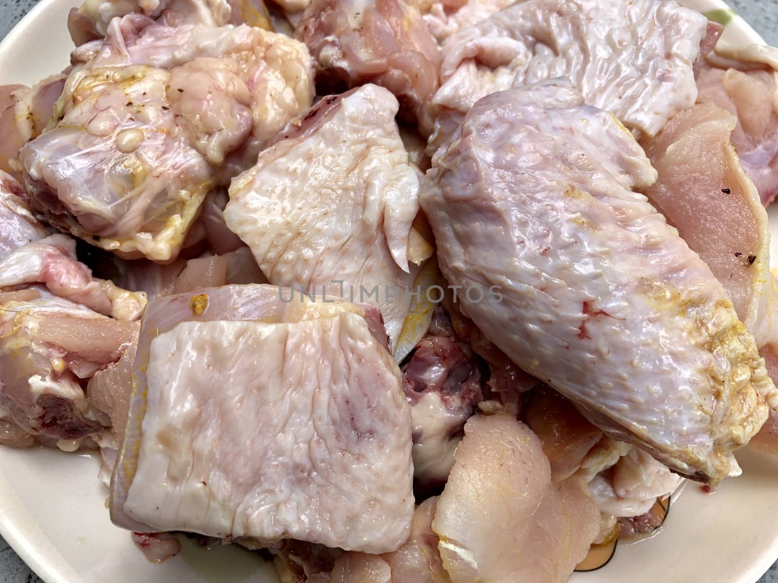 Small pieces of raw chicken meat kept in a plate for cooking