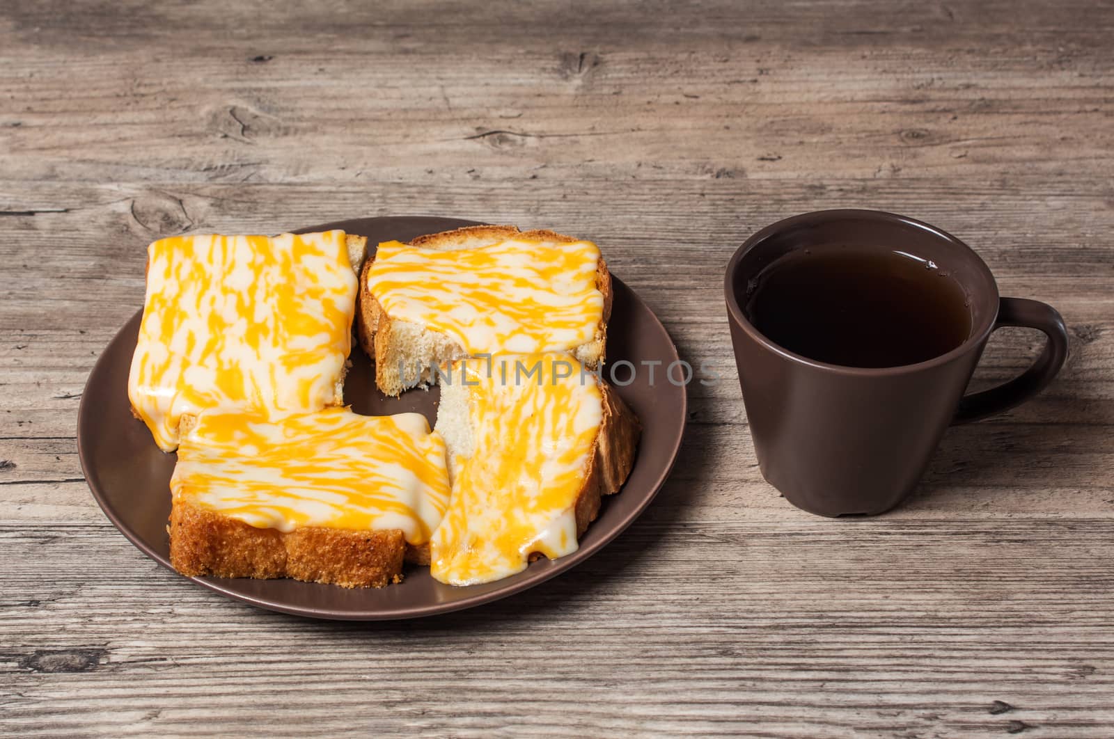 A Cup of coffee with fresh toast with melted cheese on a wooden  by YevgeniySam