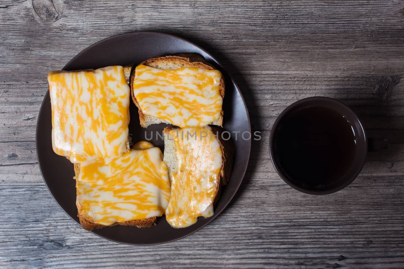 A Cup of coffee with fresh toast with melted cheese on a wooden  by YevgeniySam