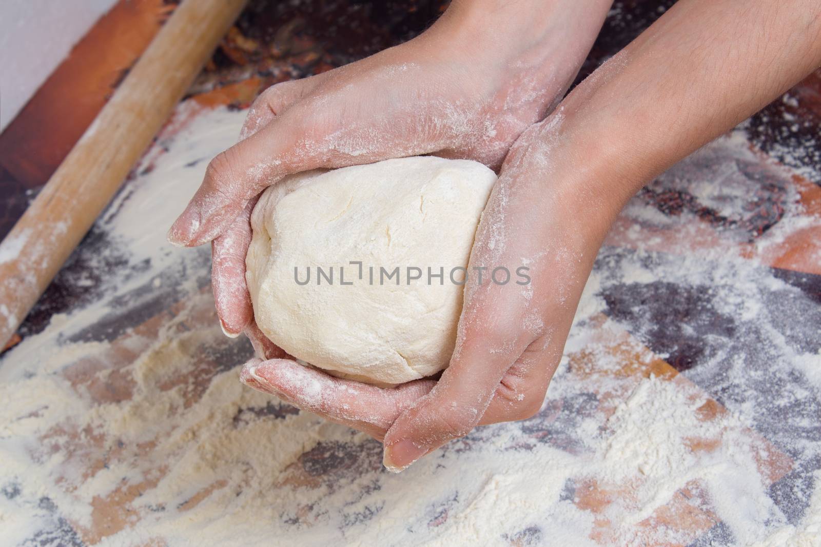 Woman preparing dough from flour. Female hands holding a piece o by YevgeniySam