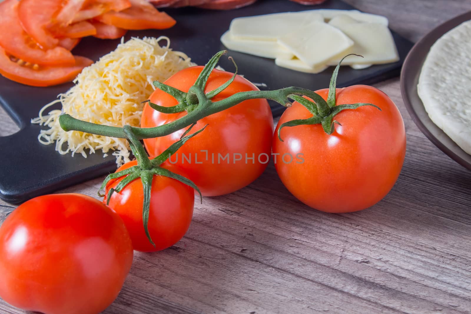 Tomatoes, sausage and cheese are on the cutting Board on the kitchen table. We cook at home