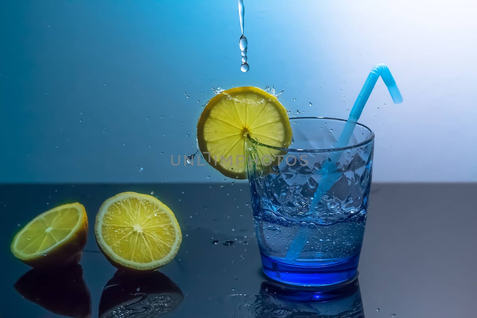 Splashes of water fall into a glass with lemon and ice.A mug of  by YevgeniySam