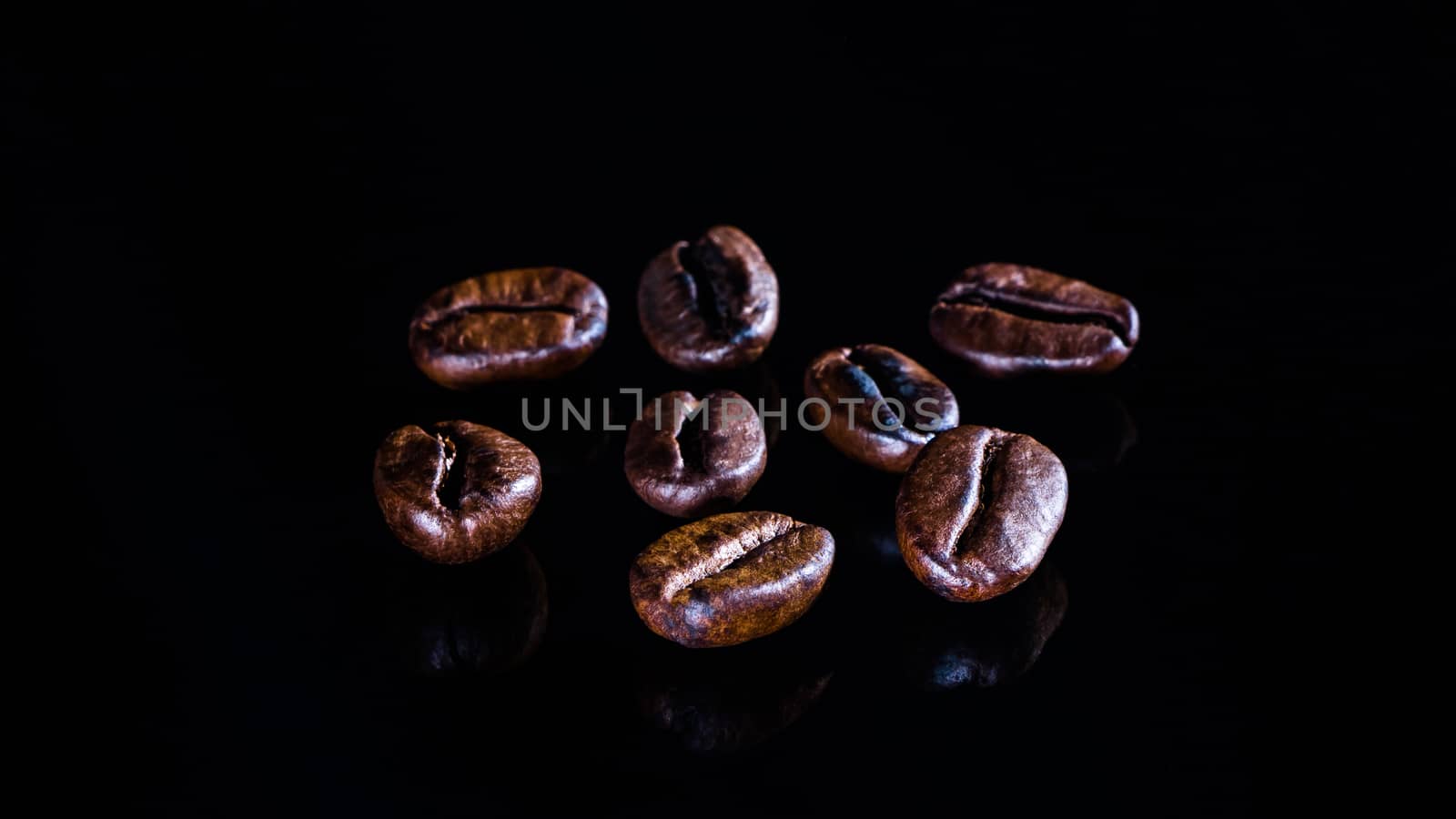 Coffee beans on a black mirror background close-up.