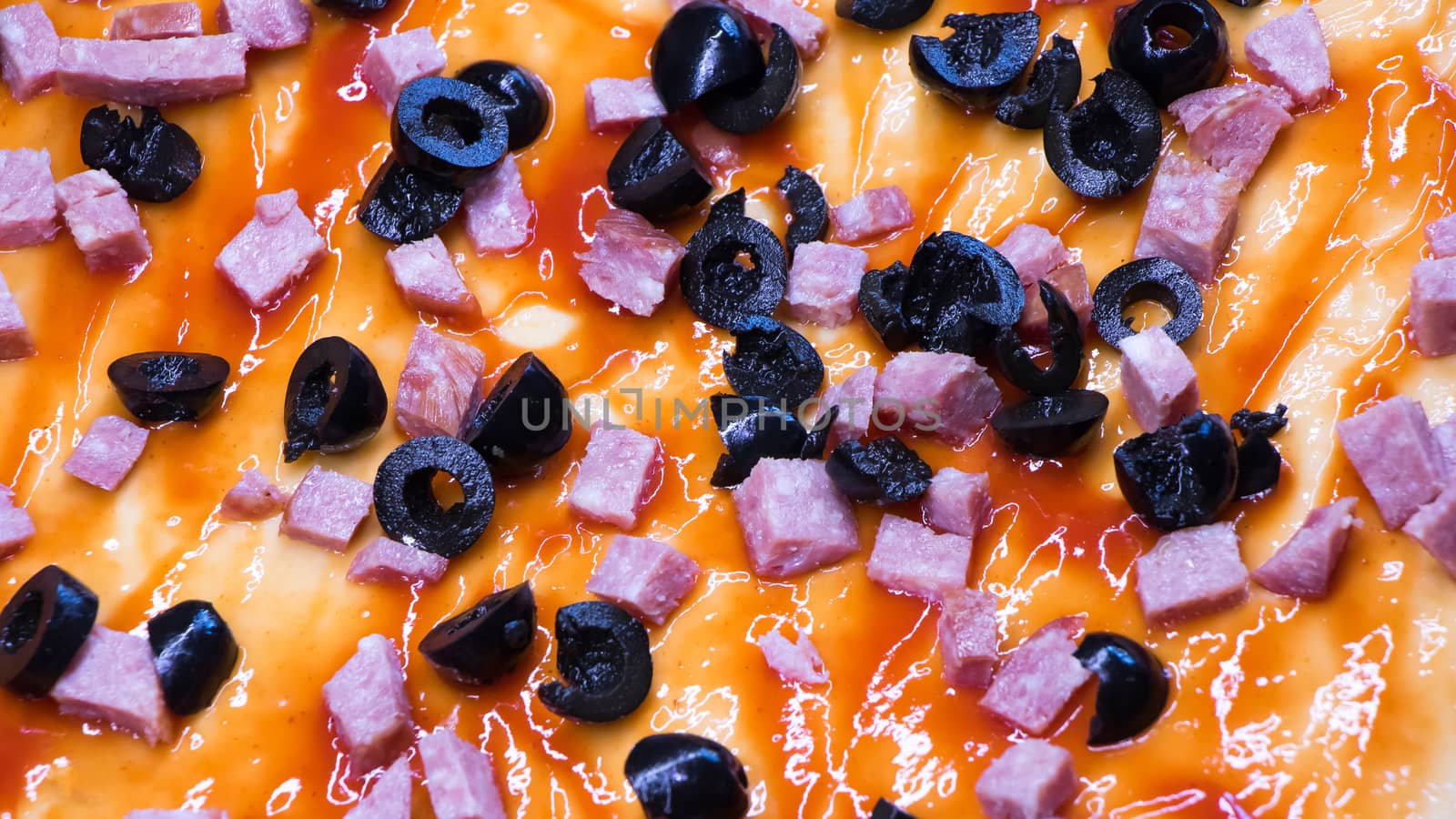 Ingredients on raw pizza close-up.Olives and sliced sausage lie  by YevgeniySam